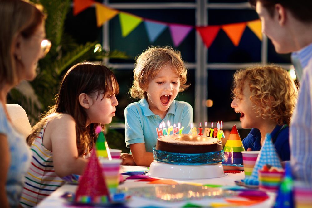 A group of children are blowing out candles on a birthday cake.