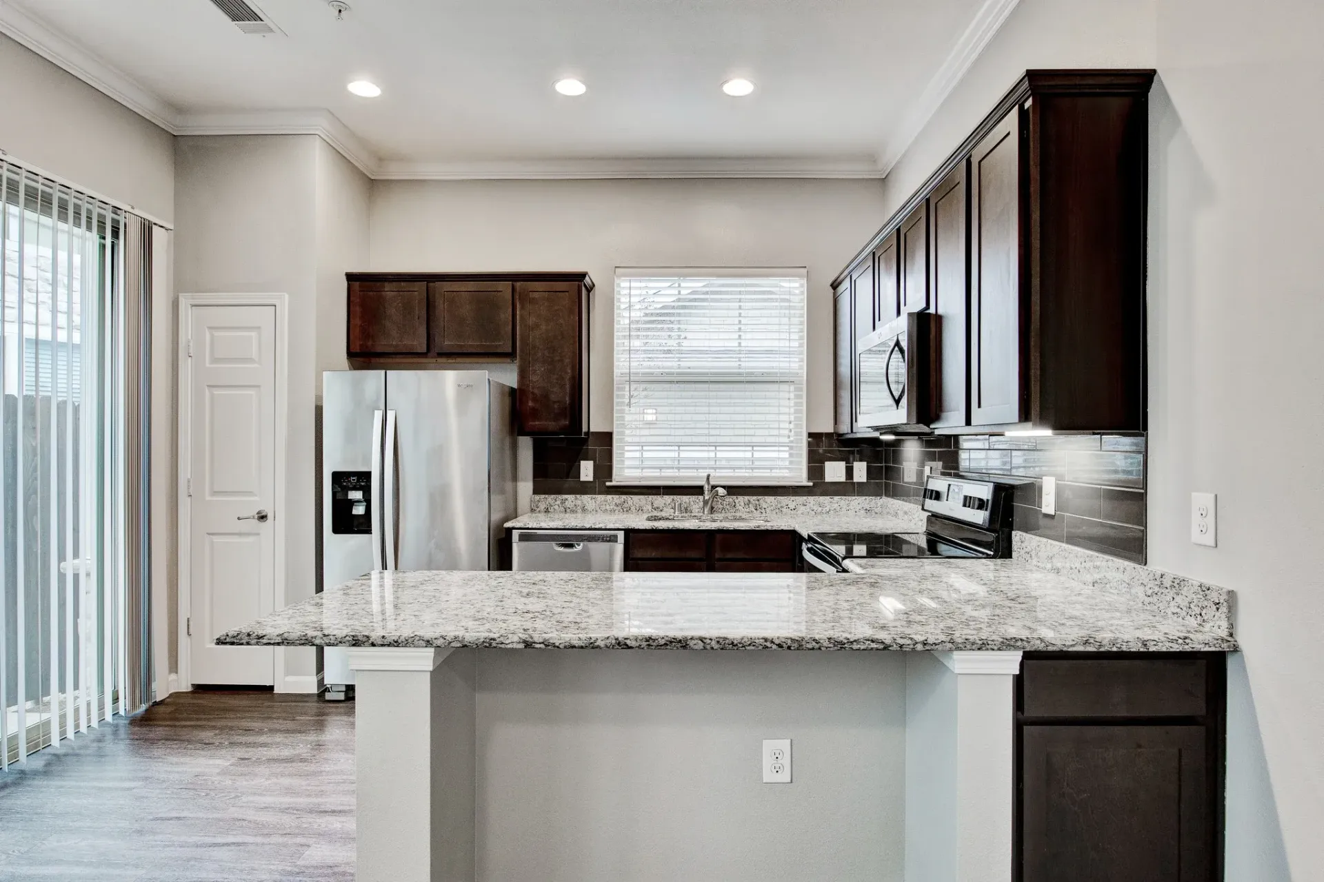 A kitchen with granite counter tops and stainless steel appliances.