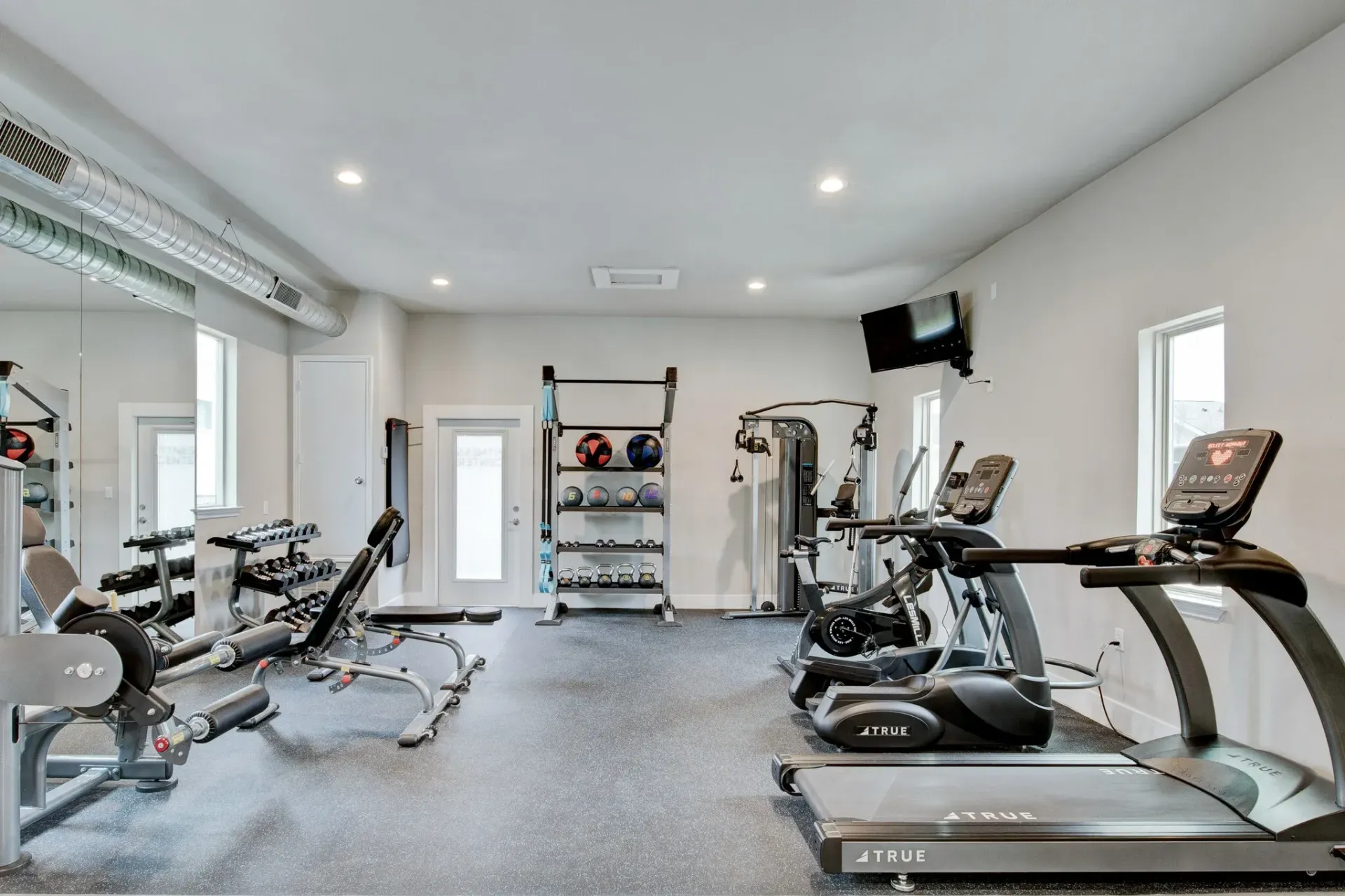 A gym with treadmills, dumbbells, and a mirror.