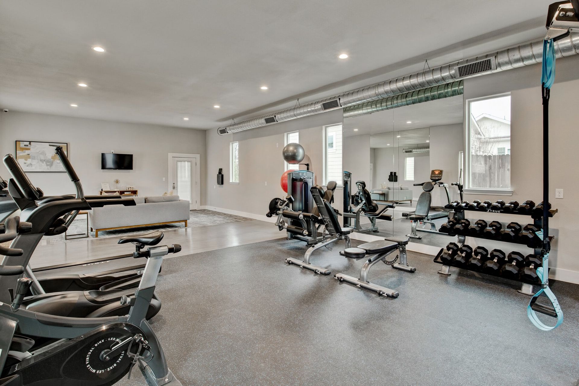 A large gym with a lot of exercise equipment and a large mirror.