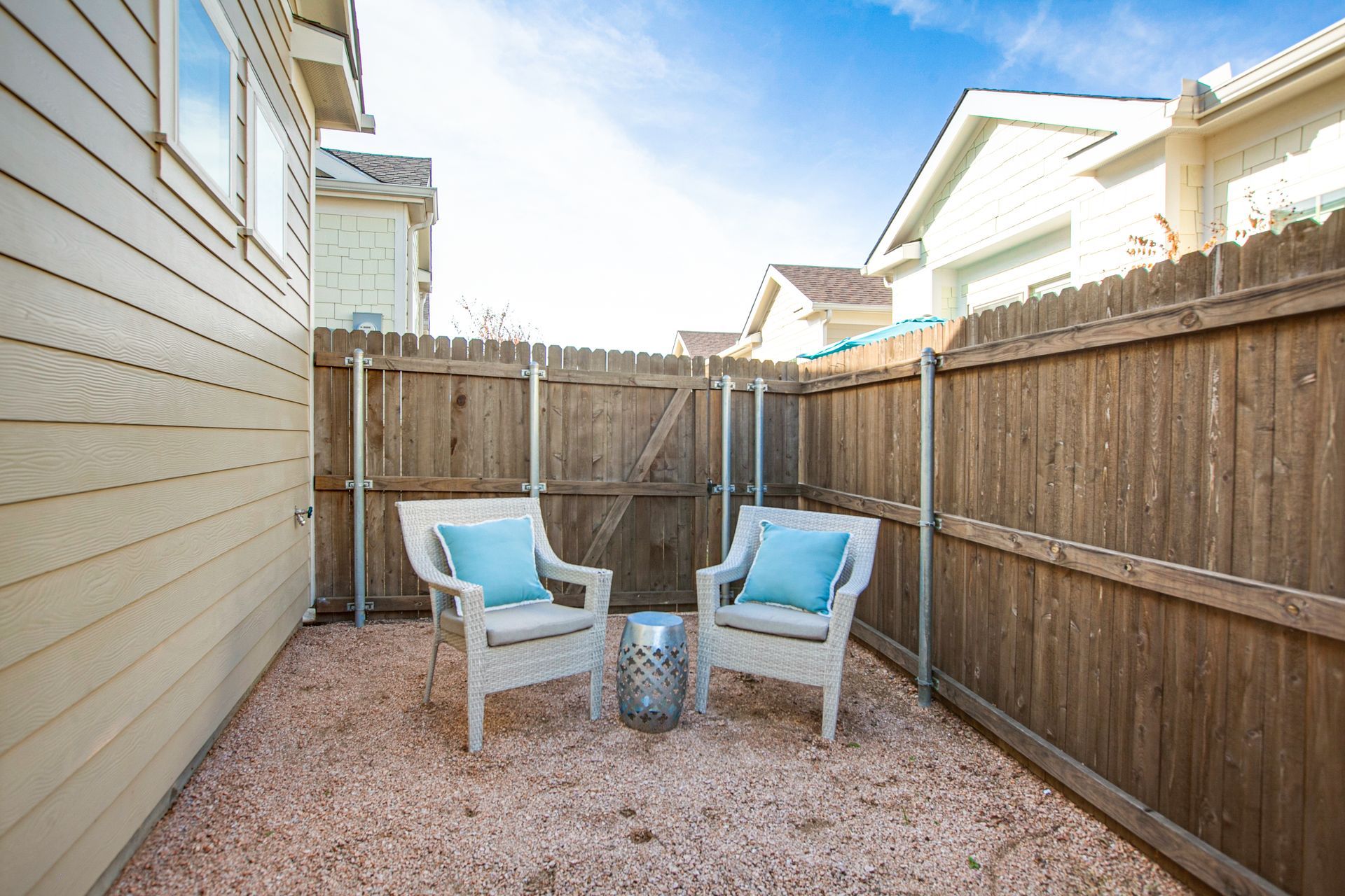There are two chairs and a table in the backyard of a house.