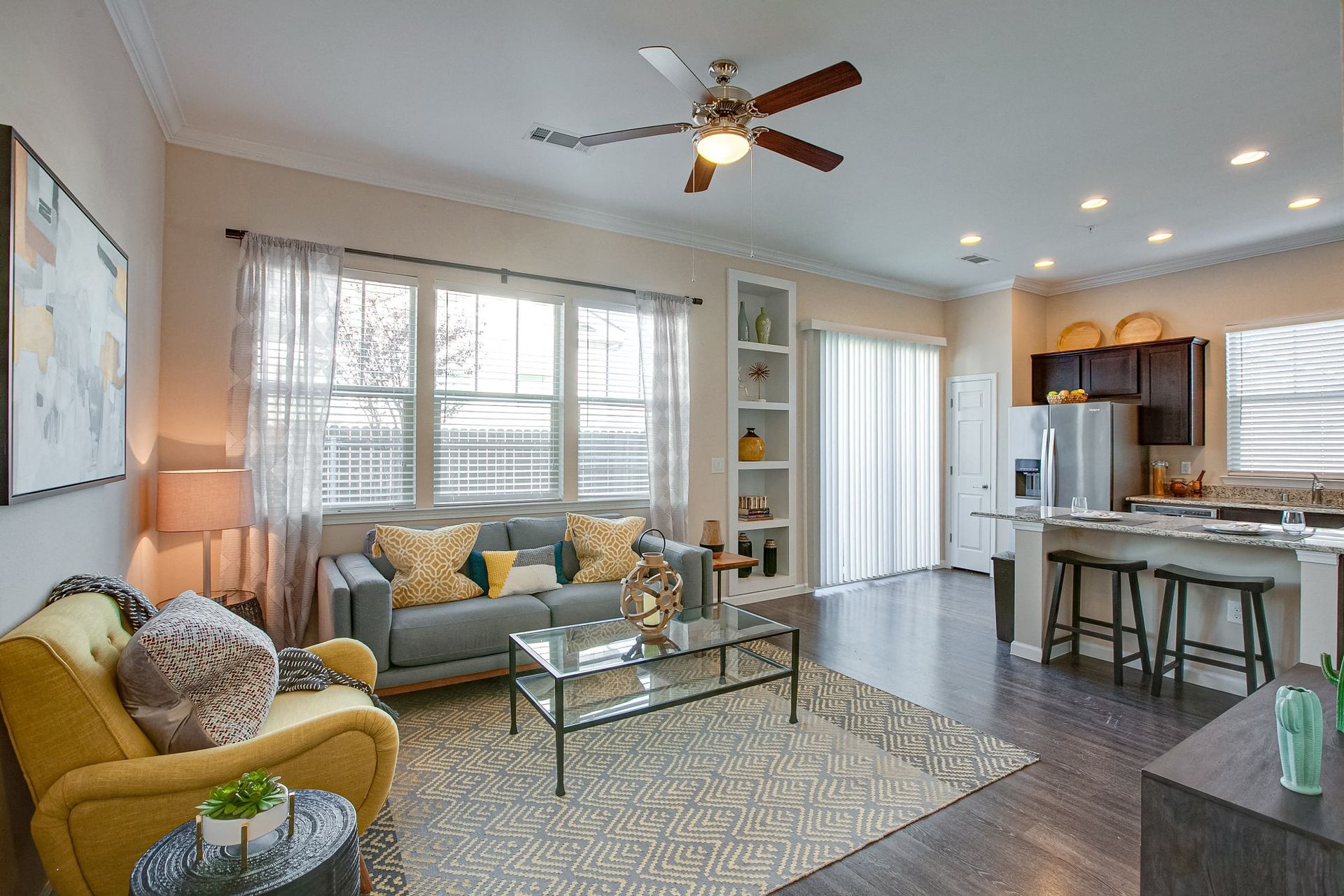 A living room with a couch, chair, coffee table, and ceiling fan.