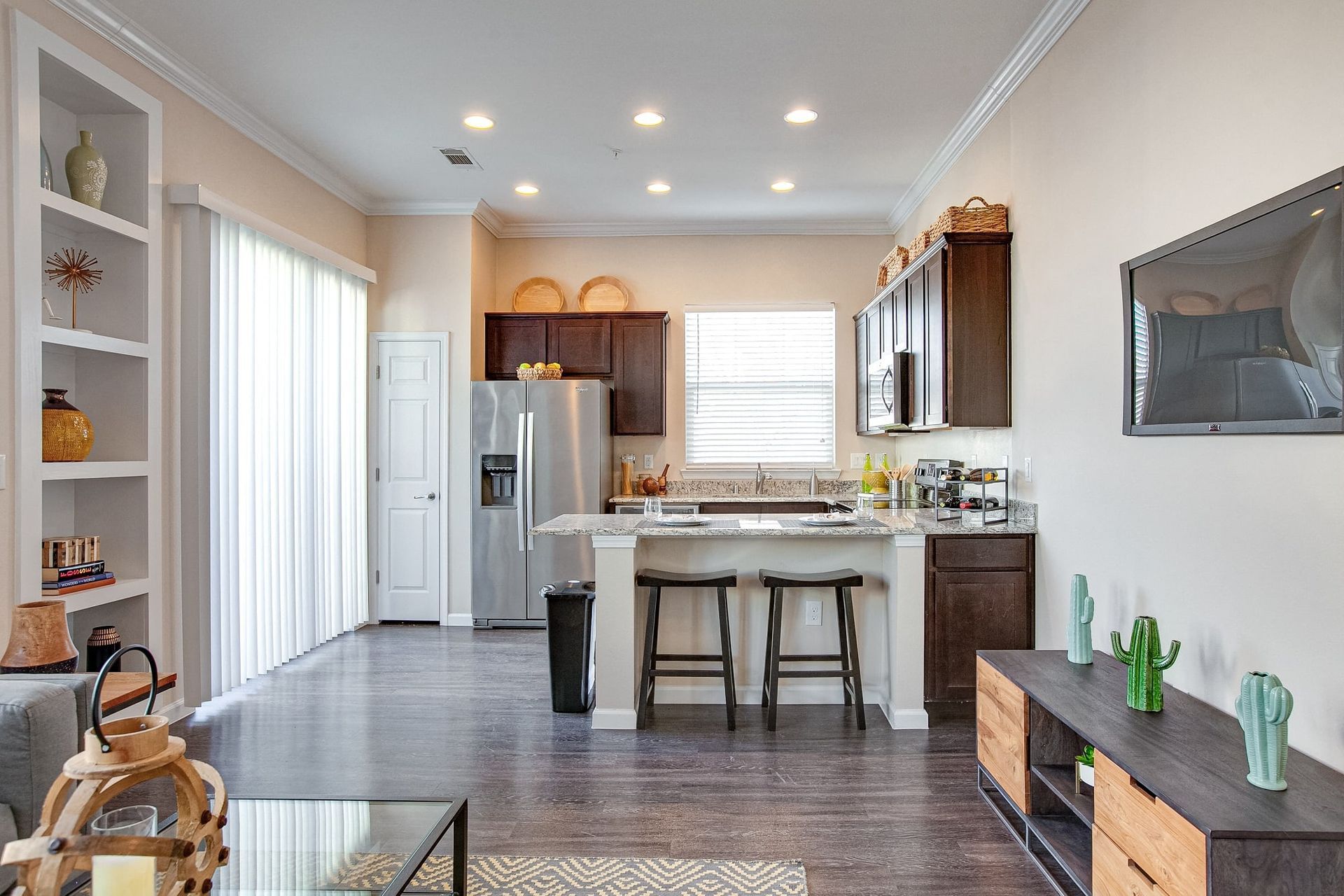 A living room and kitchen in a house with a flat screen tv on the wall.