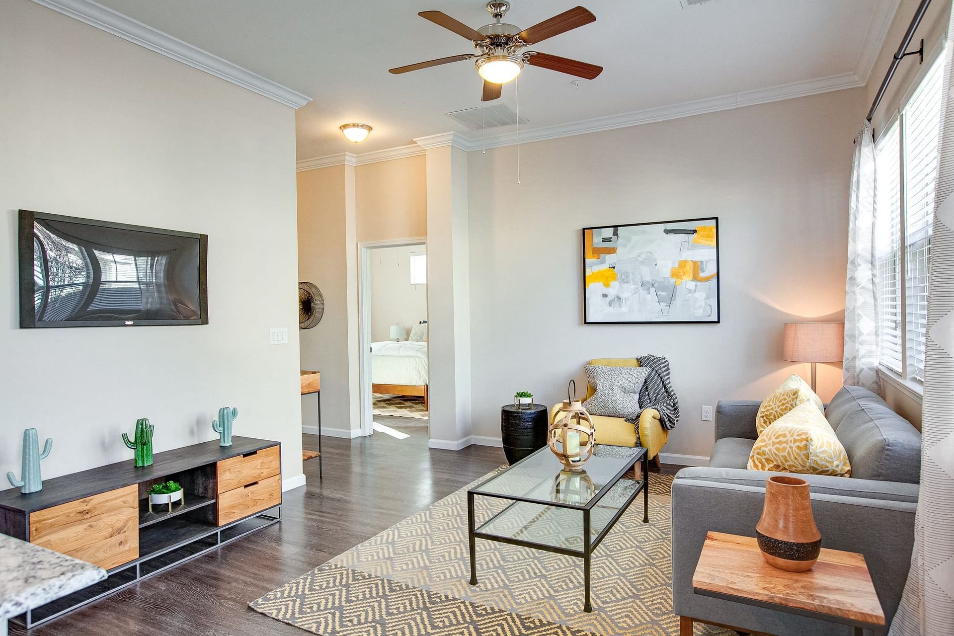 A living room with a couch, chair, coffee table, television, and ceiling fan.