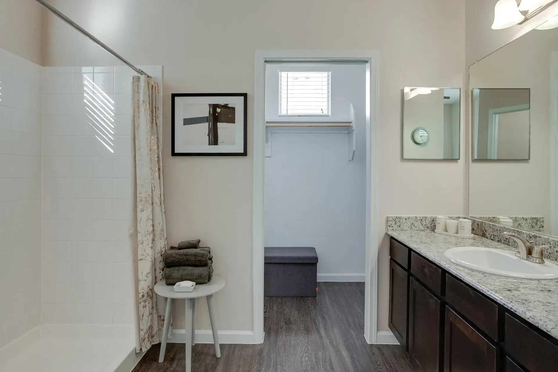 A bathroom with a sink, mirror, and walk in closet.