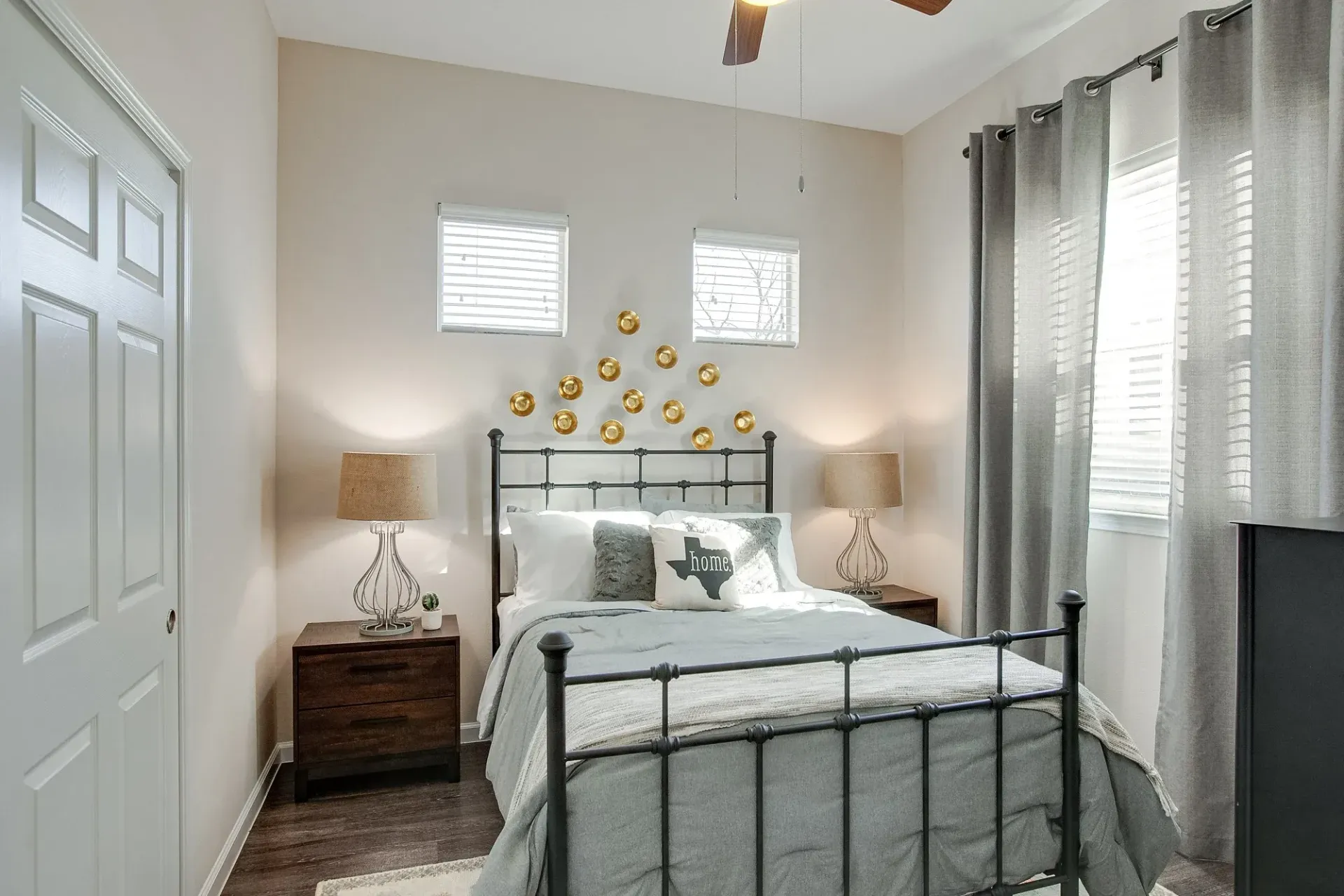 A bedroom with a bed, nightstands, lamps, and a ceiling fan.