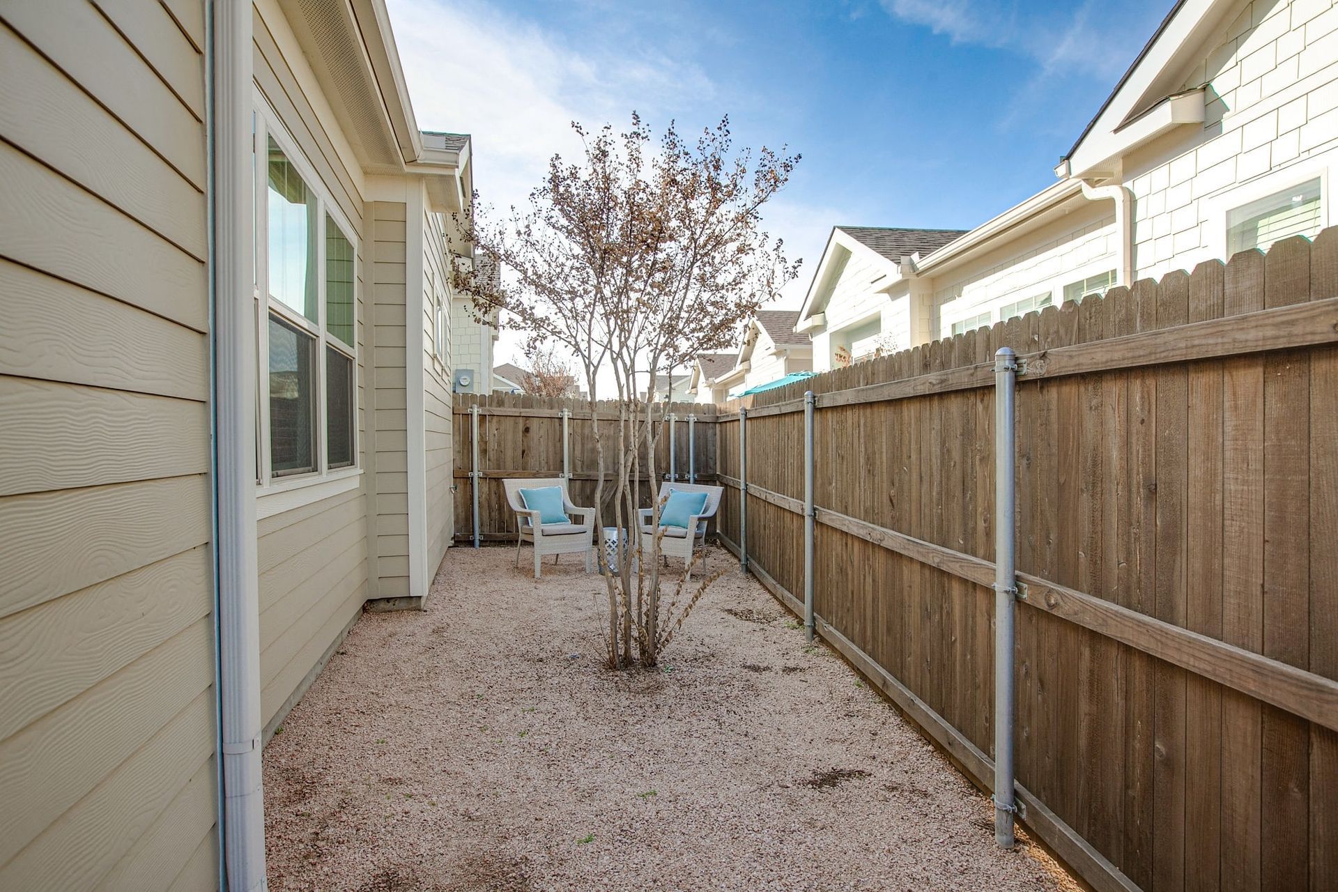 The backyard of a house with a wooden fence and a tree.