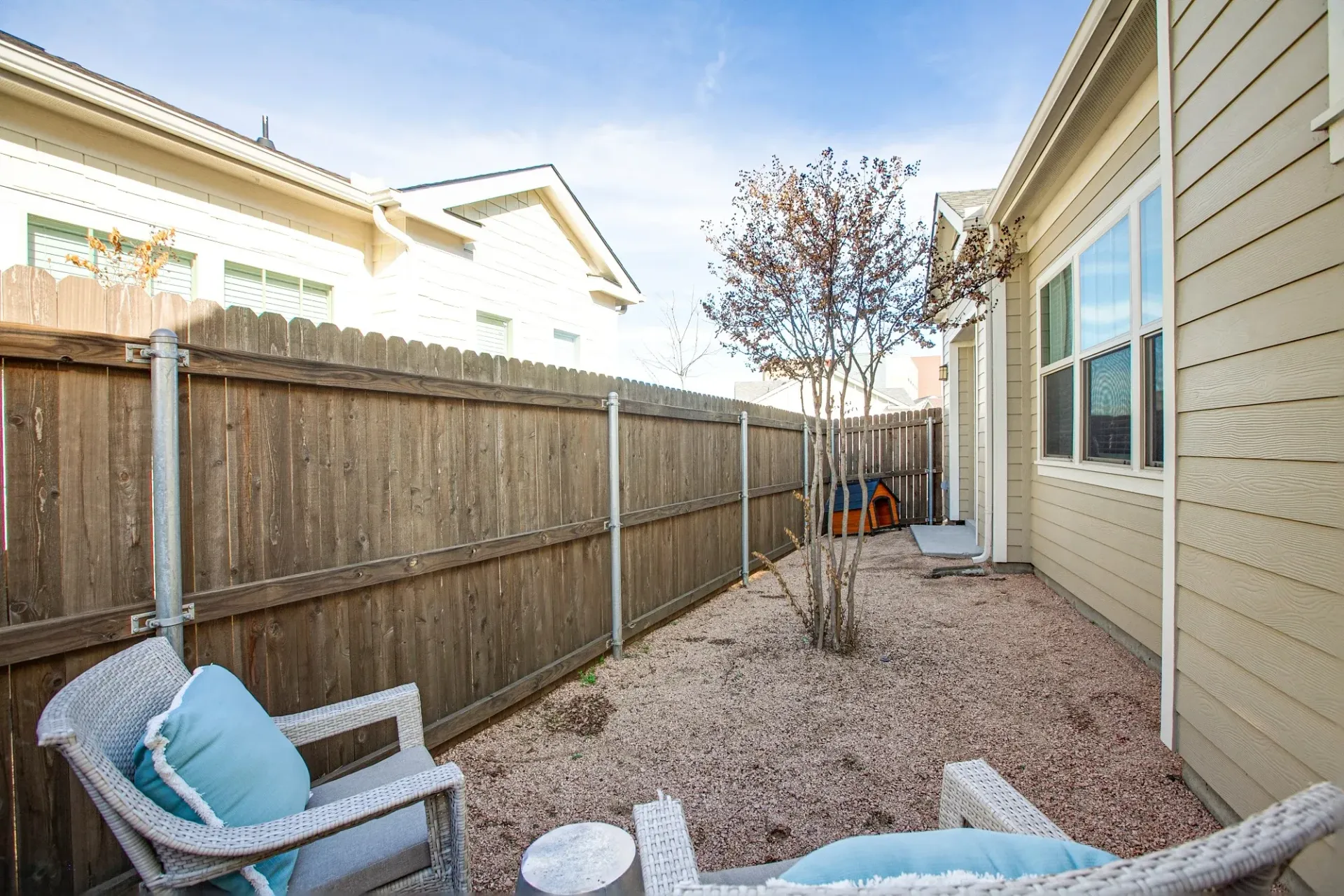 A backyard with a wooden fence, chairs, and a table.