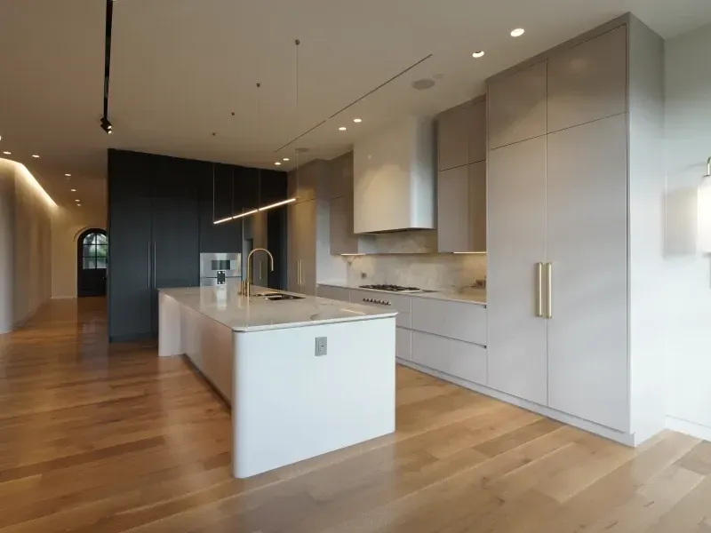 Modern kitchen with a white island, light gray cabinetry, and hardwood floors.