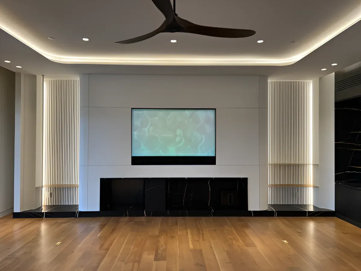 Modern living room wall with a centered television, built-in black shelving, vertical wood slats, and recessed lighting.