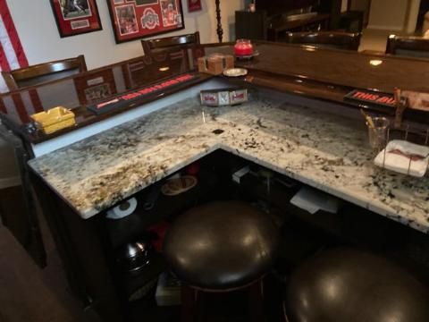 A bar with a granite counter top and stools in a living room.