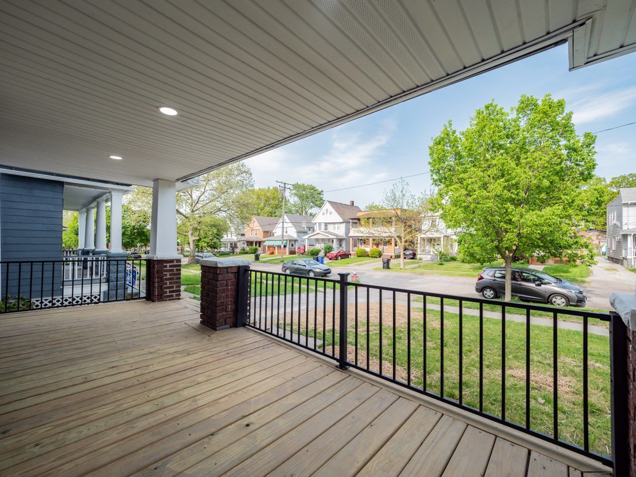 A porch with a railing and a view of a residential neighborhood.