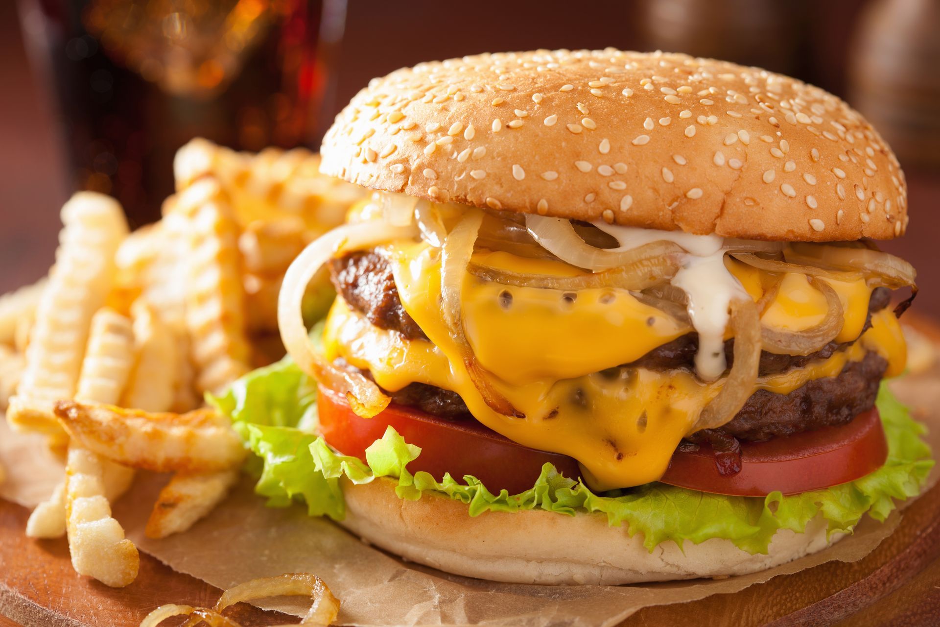 A hamburger and french fries are on a wooden table.