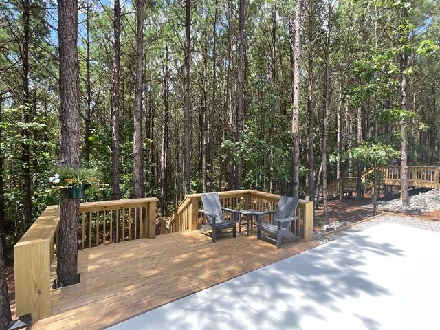 A wooden deck with chairs and a table in the middle of a forest.