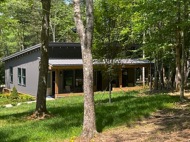 A small house is surrounded by trees in the middle of a forest.