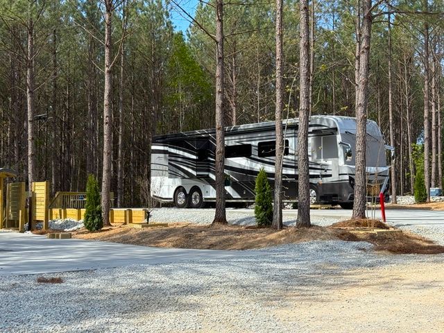 An rv is parked in a parking lot surrounded by trees.