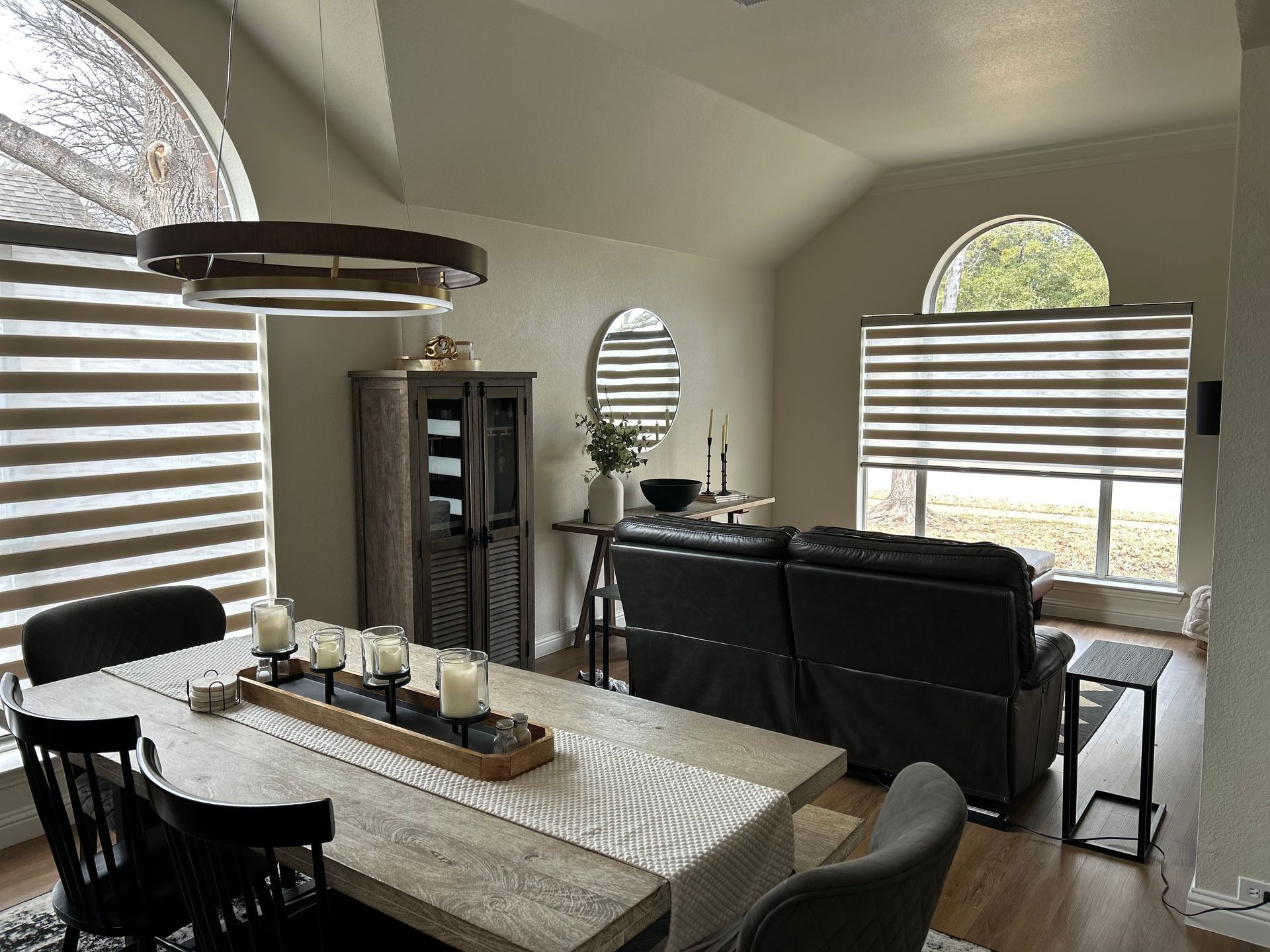 Dining area with a table, chairs, sofa, windows, and overhead light.