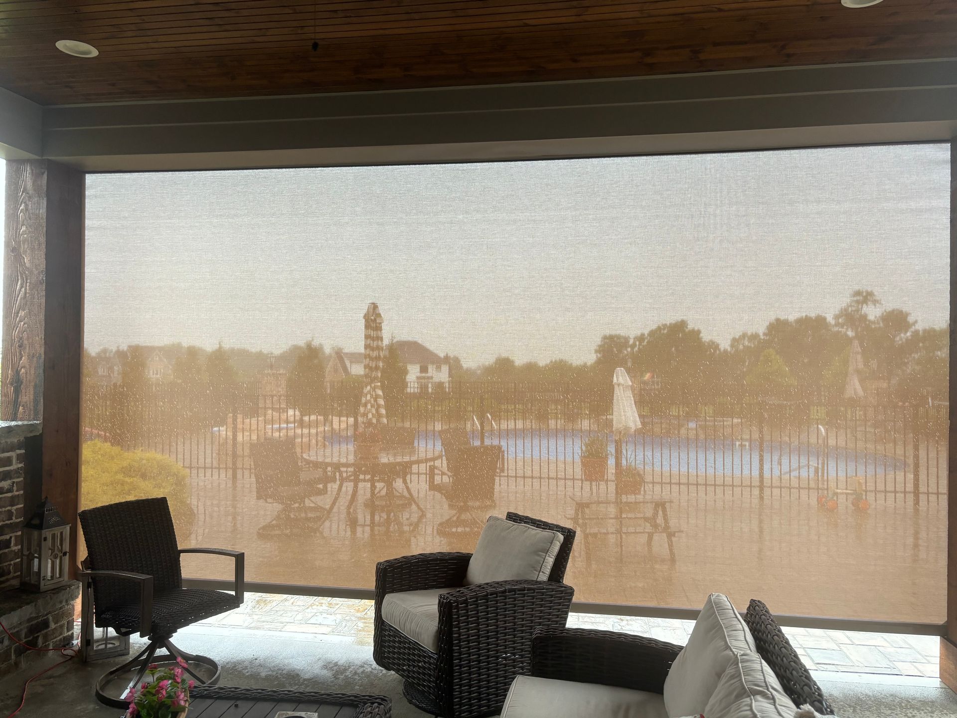 Patio with shade screen overlooking a pool area. Outdoor seating visible.