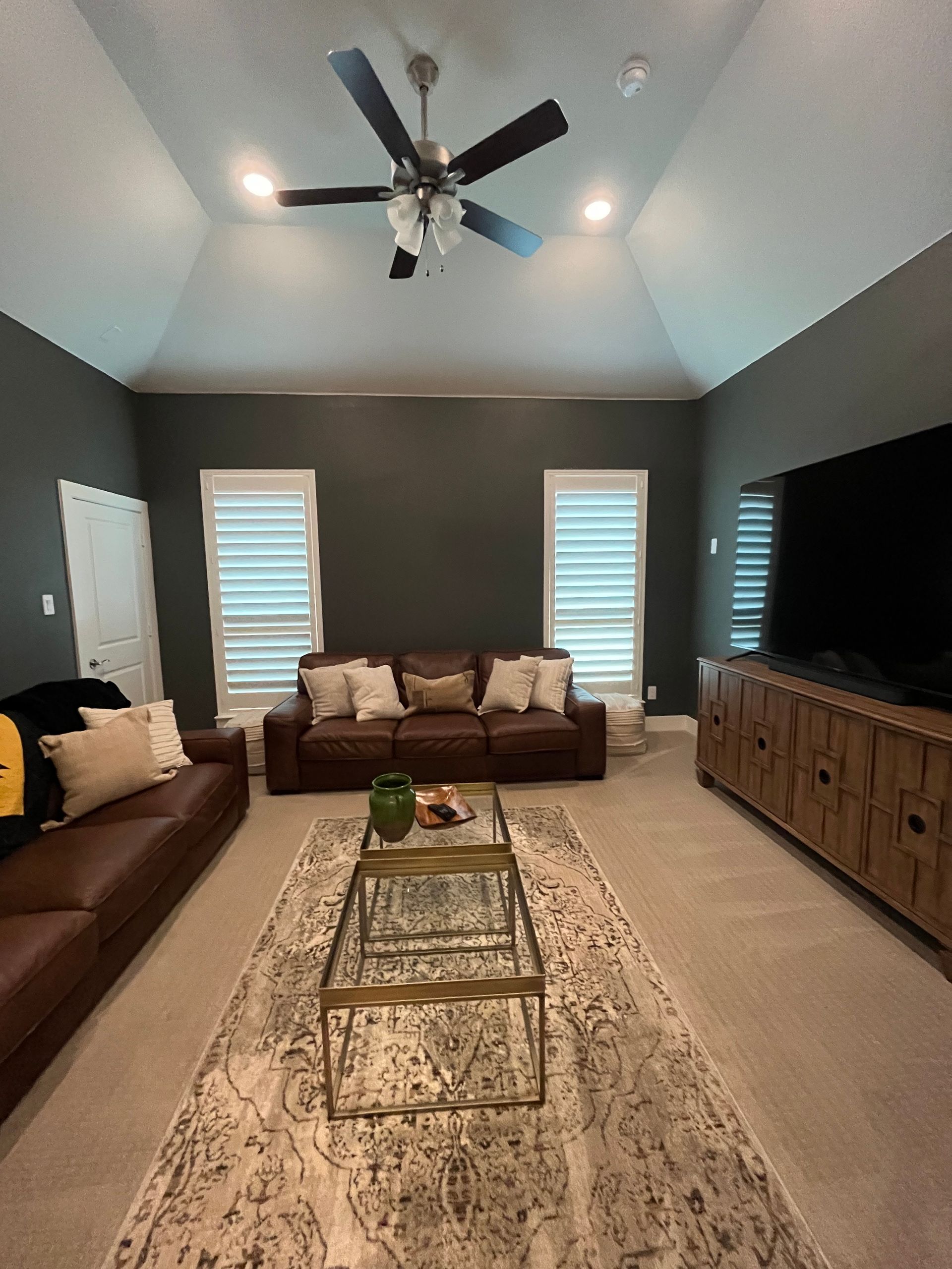 Living room with brown leather sofas, patterned rug, and dark gray walls.