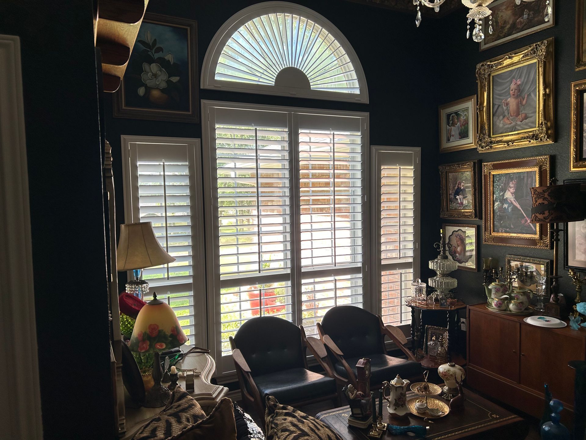 Dark room with shuttered windows, art, and furniture.