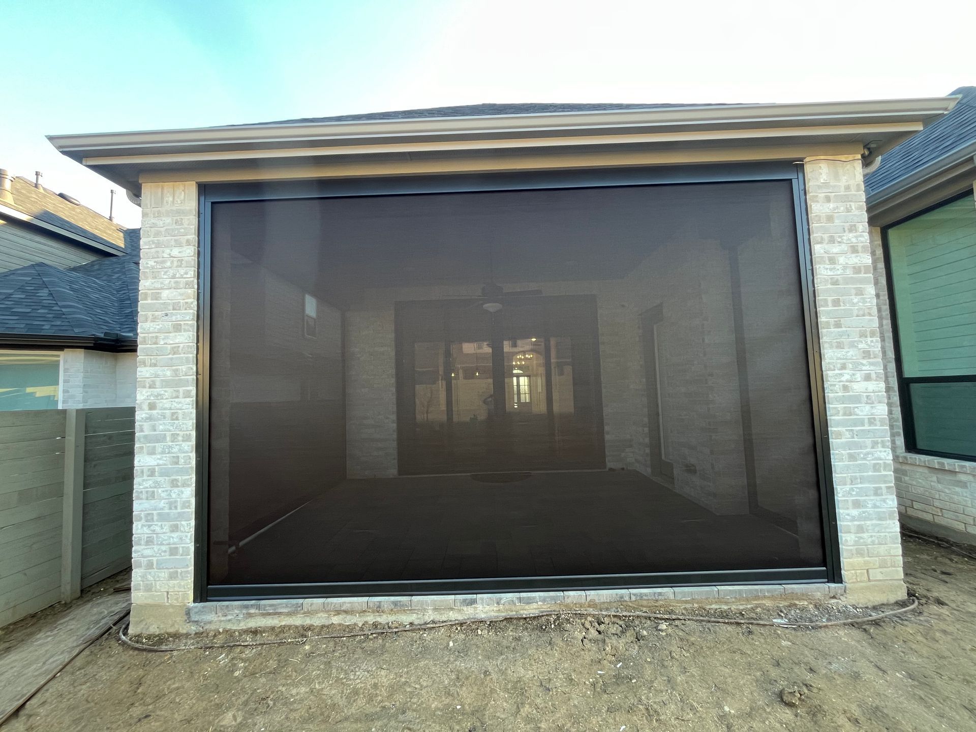 A brick patio enclosure with a large retractable screen, viewed from outside.