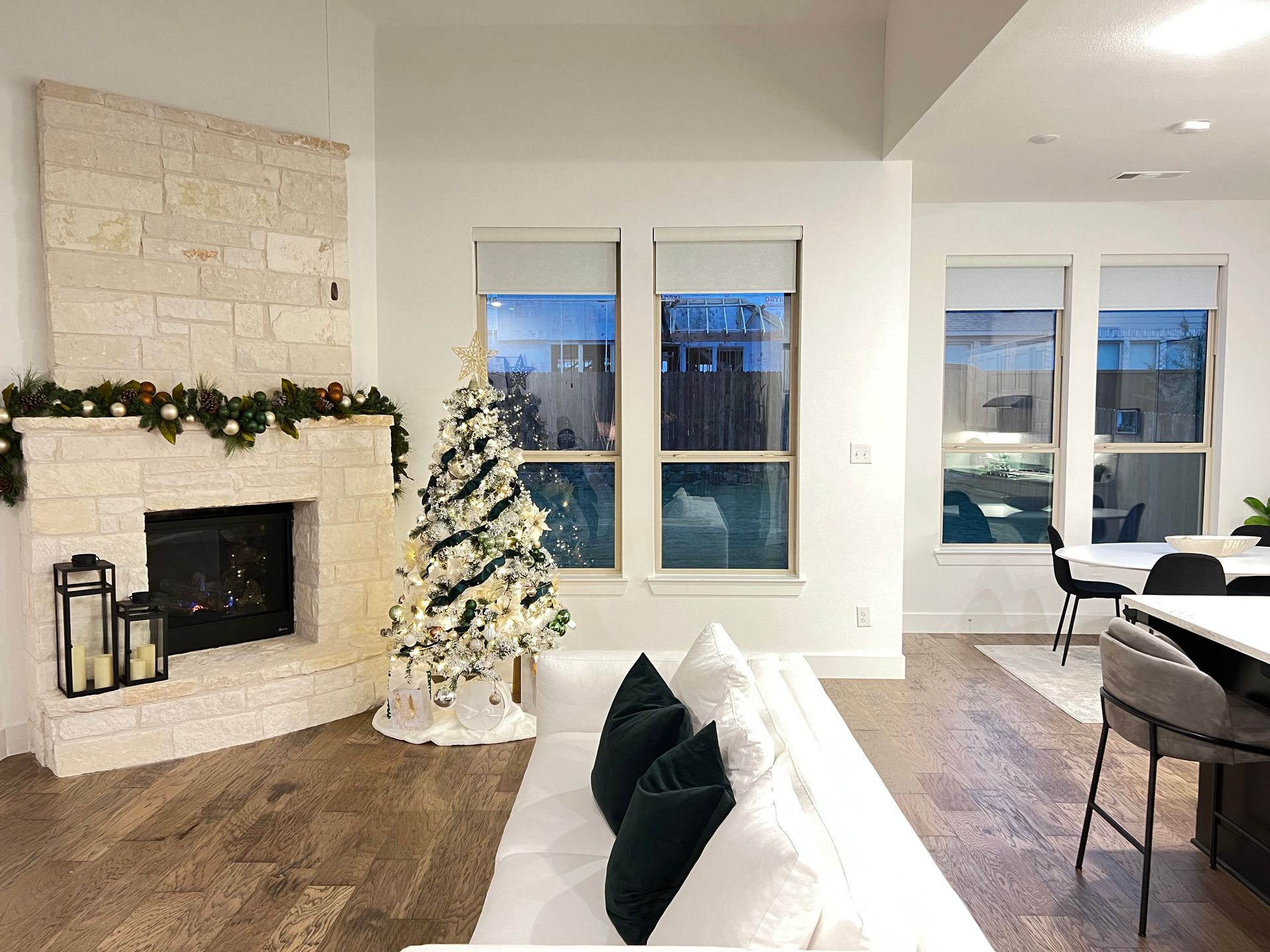 Living room with fireplace, Christmas tree, and white couch. Windows offer a view of the outside.
