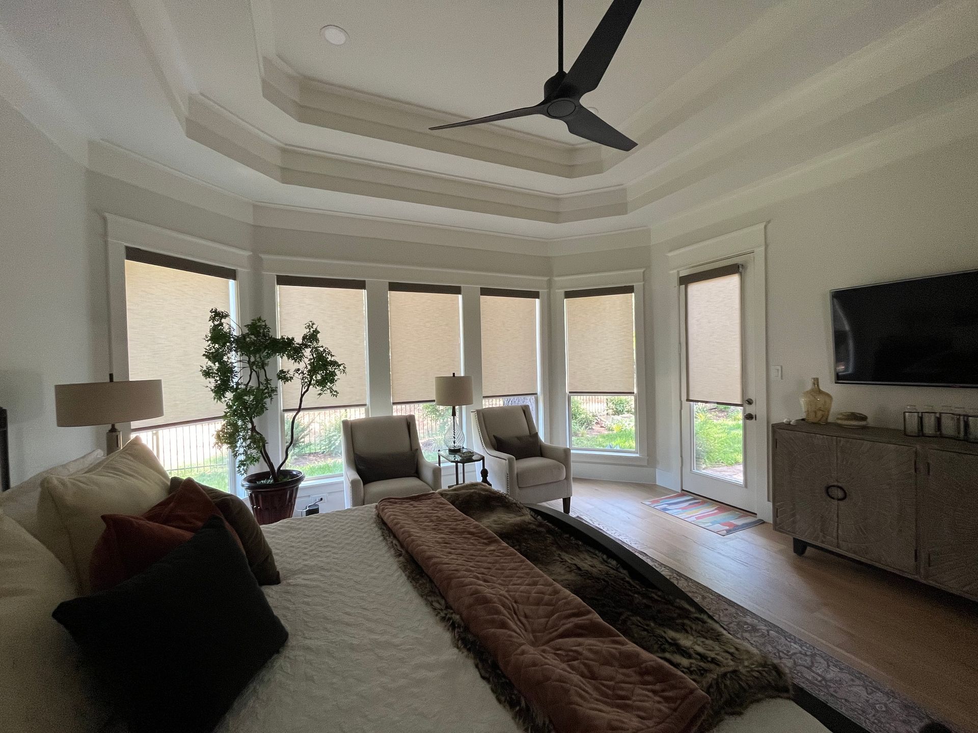 Bedroom with large bed, seating area near windows, and ceiling fan.