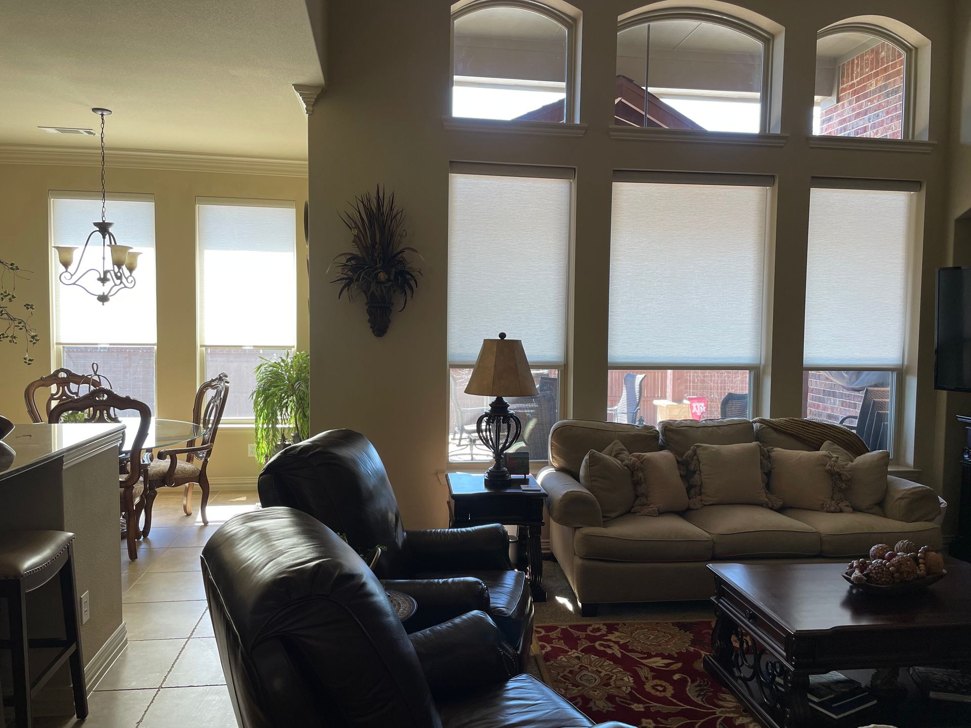 Living room with large windows, leather chairs, and a couch.