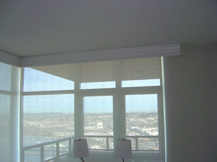 Interior corner with large windows, sheer roller shades, city view.