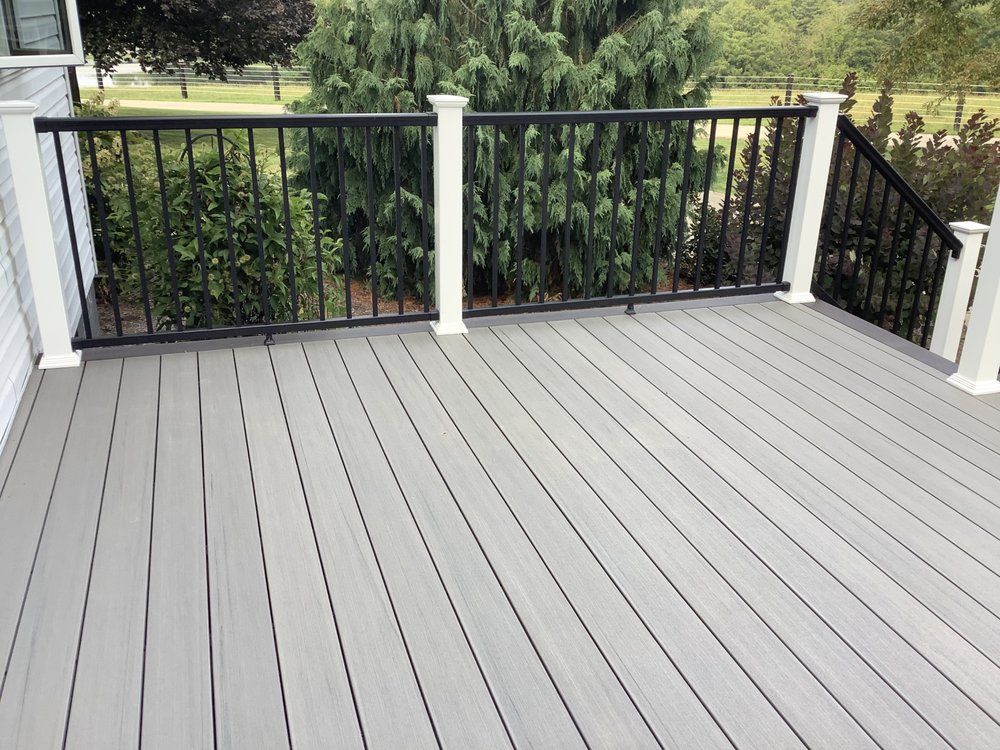 A gray deck with a black railing and stairs