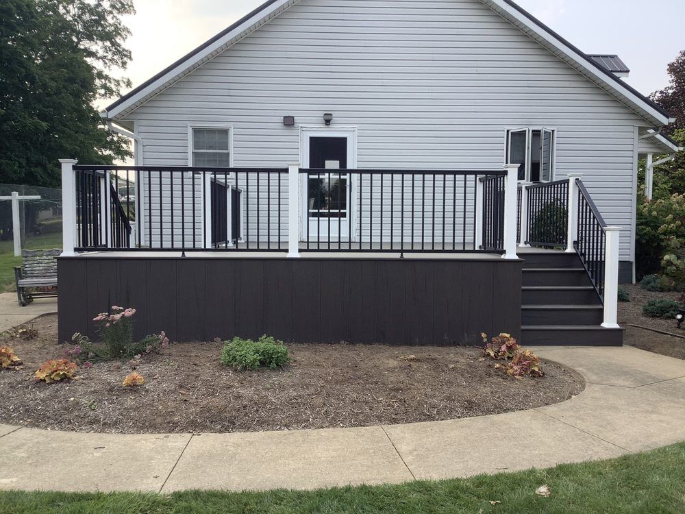 A white house with a black deck and stairs.
