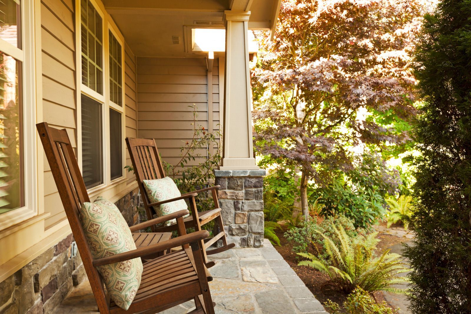 There are two rocking chairs on the porch of a house.