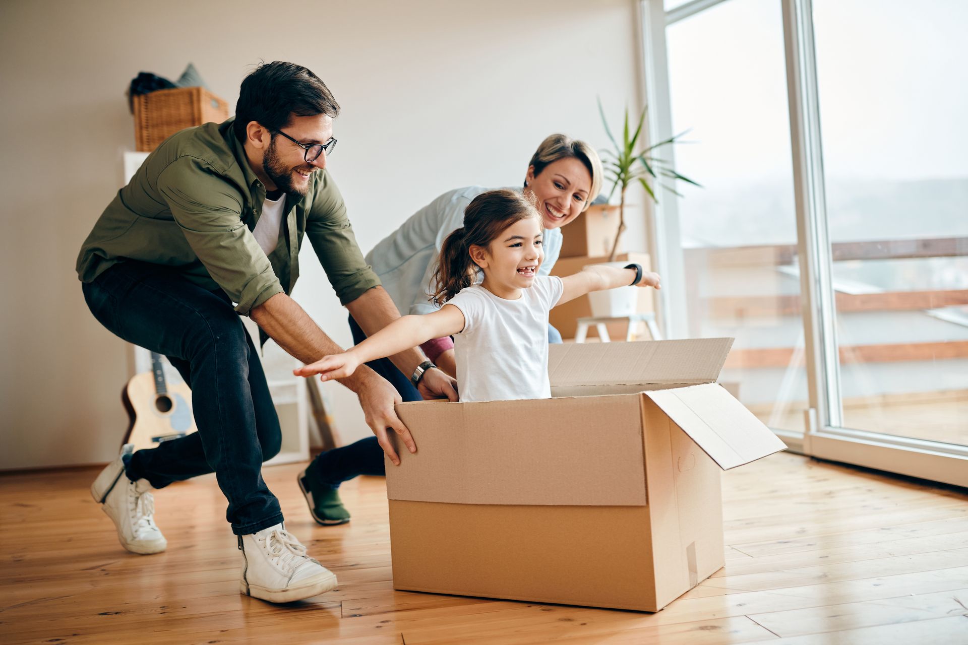 Family unpacking moving boxes in a sunlit living room