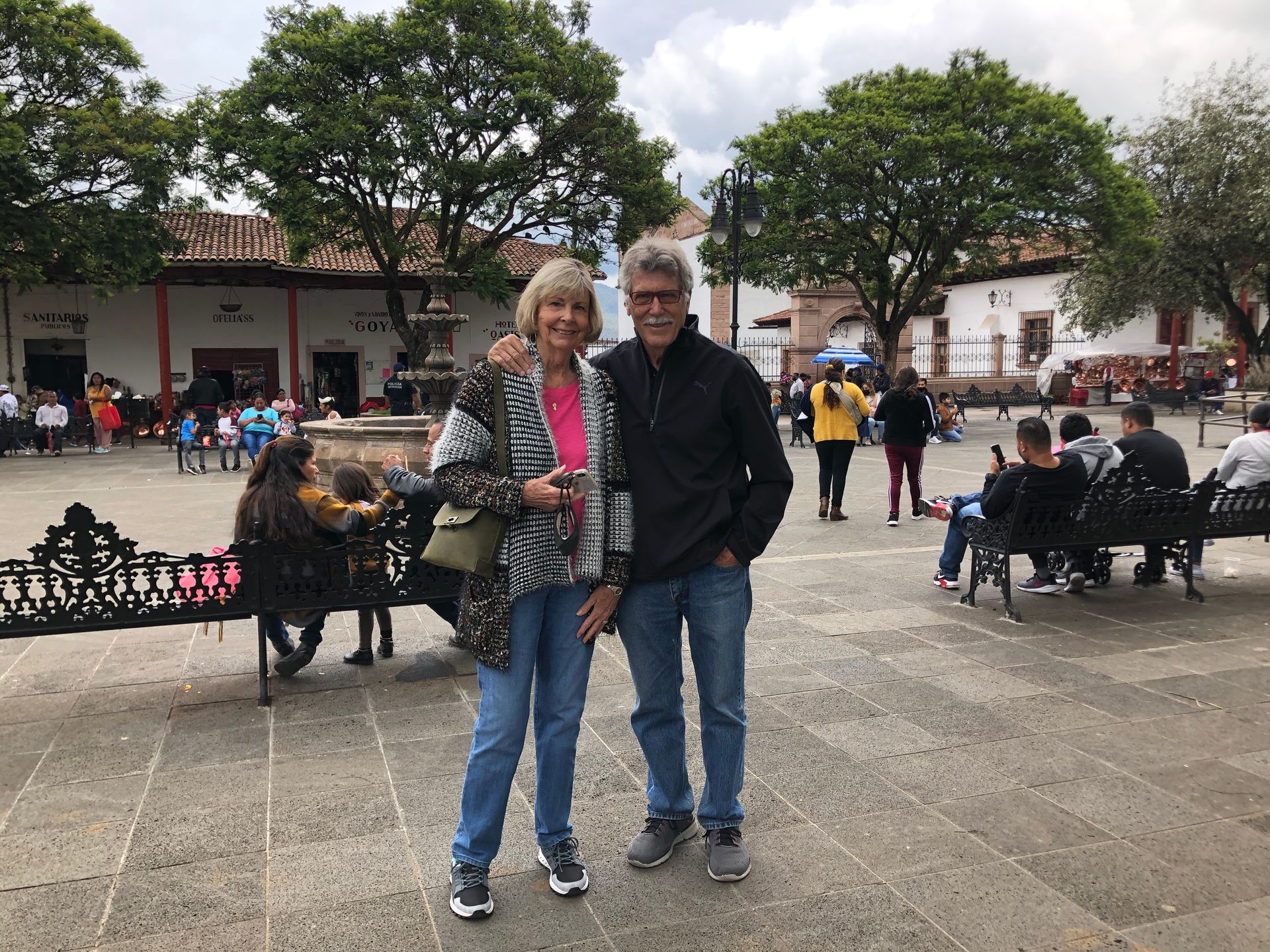 A man and a woman are posing for a picture in a park.