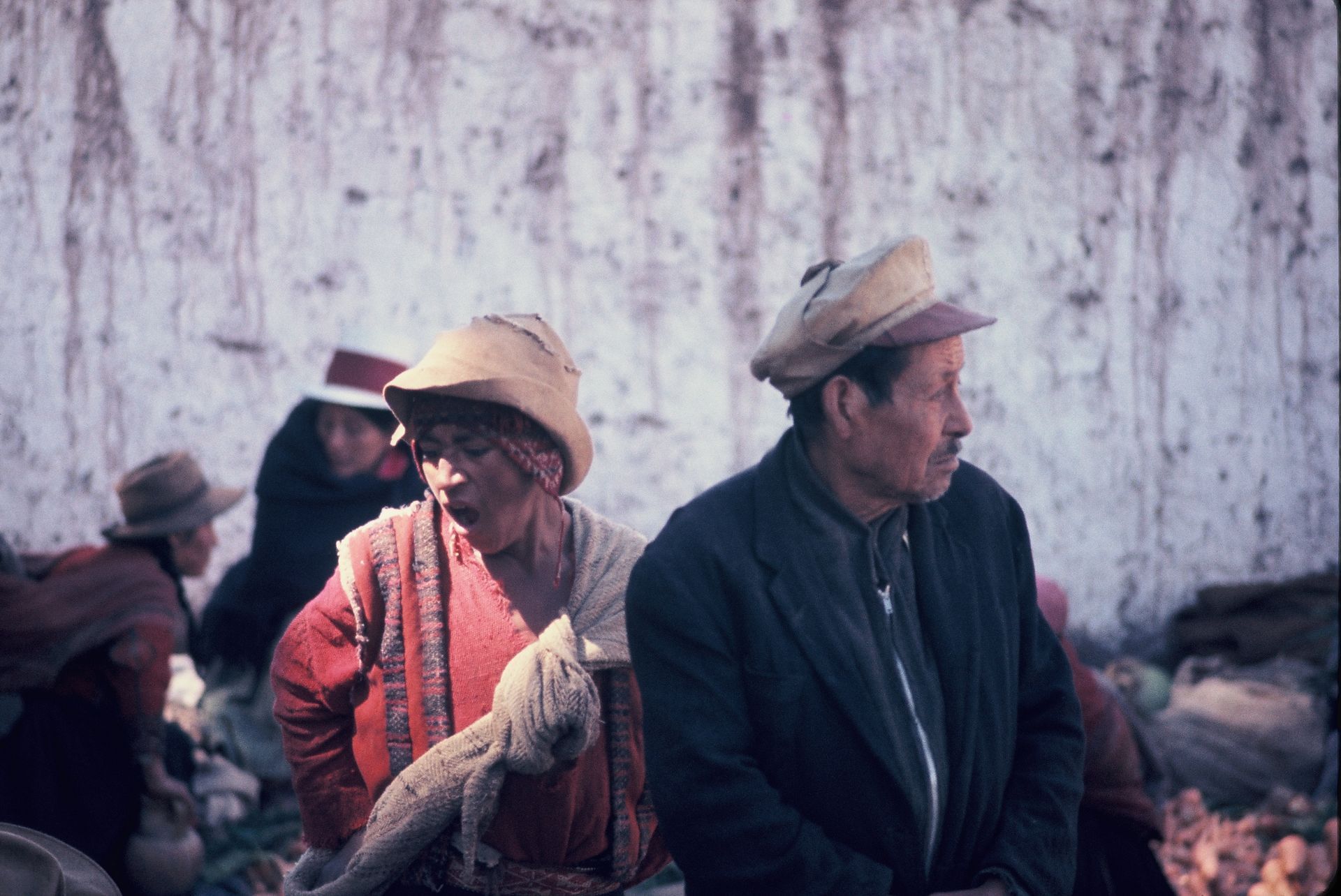 A man and a woman are sitting next to each other in front of a wall.