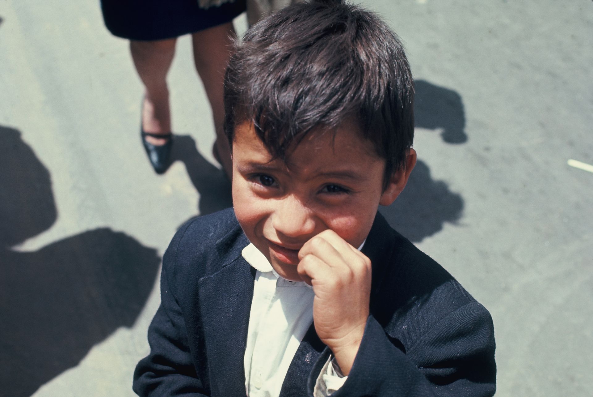 A young boy in a suit and tie is looking at the camera