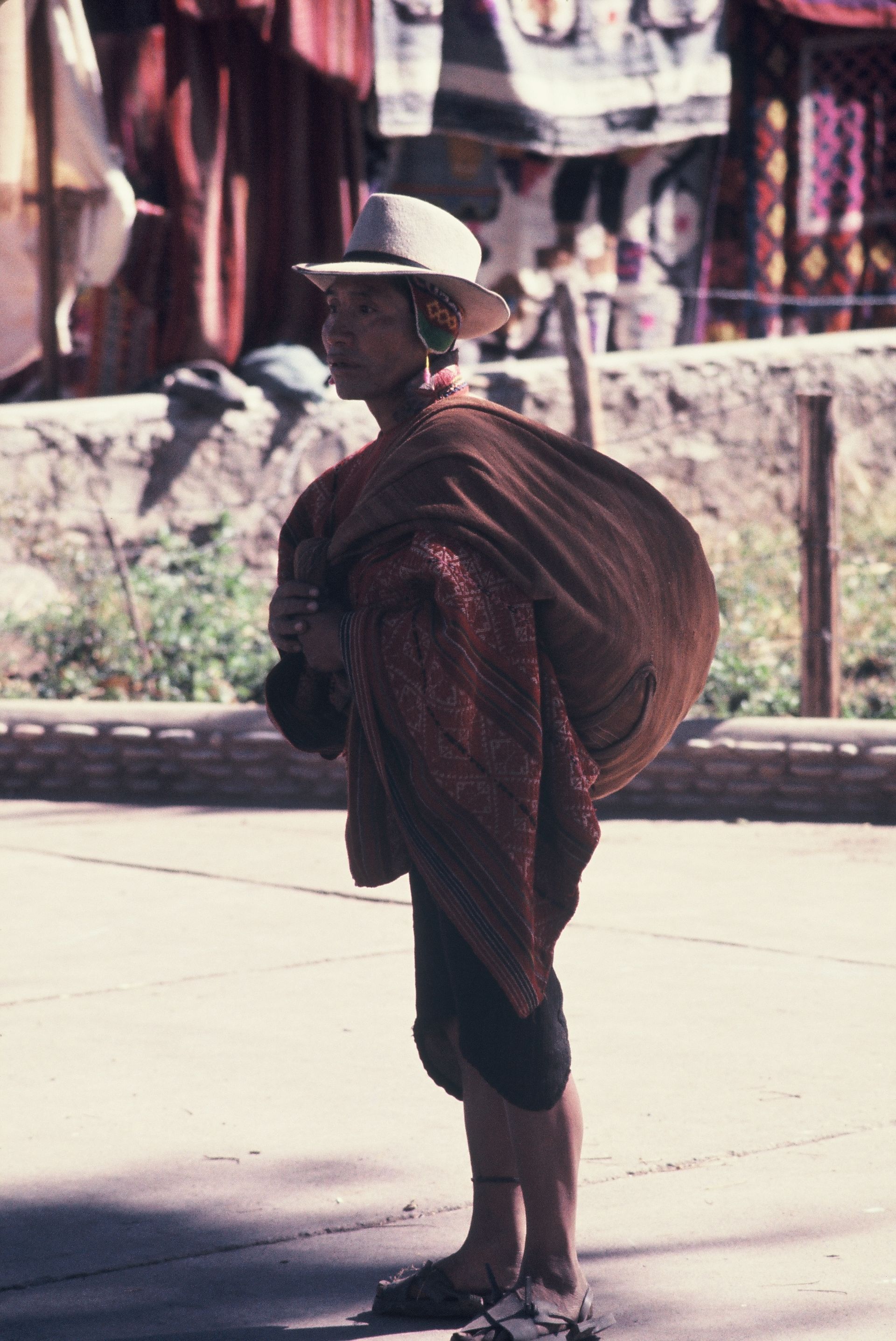 A man in a hat is carrying a large bag on his back