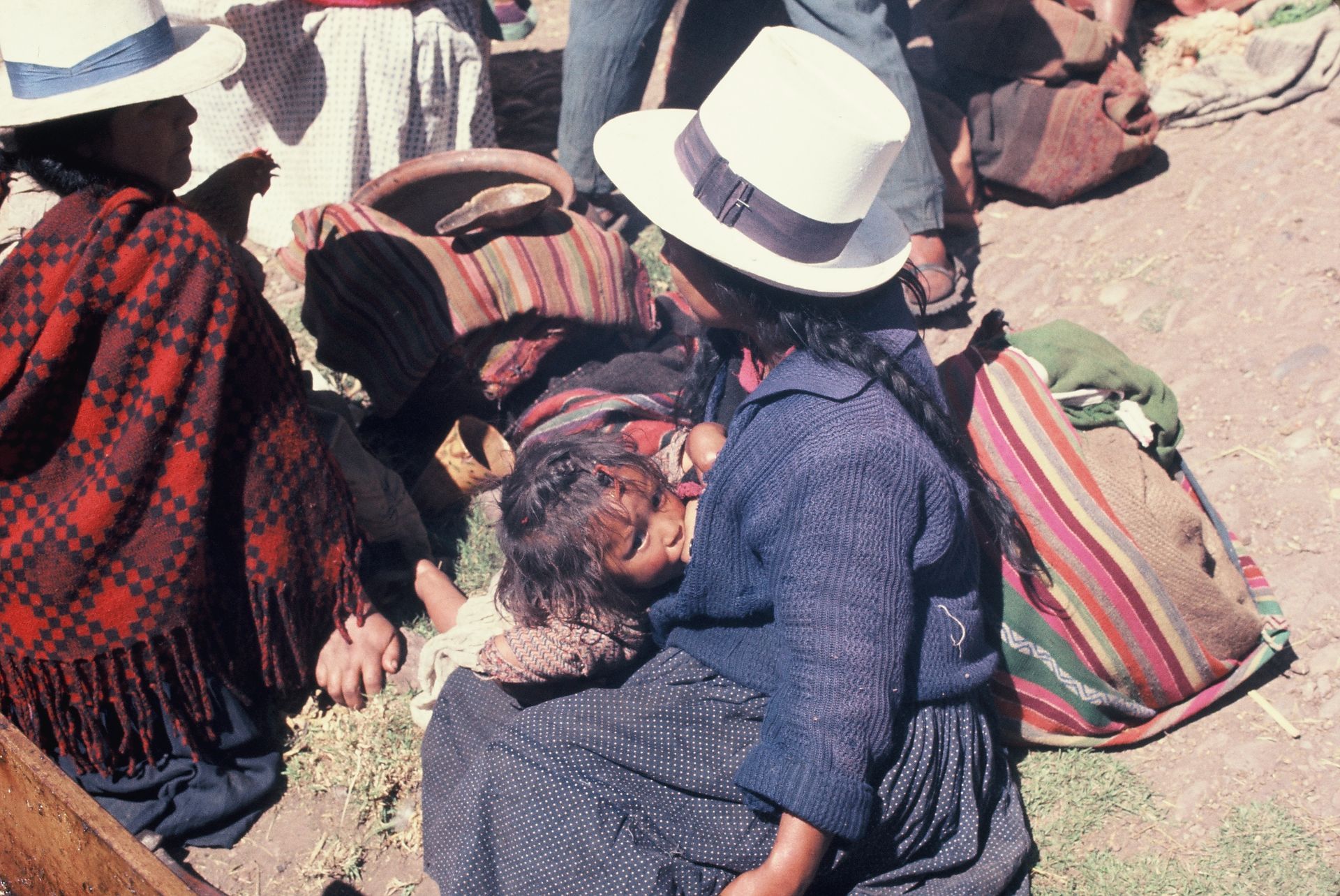 A woman is holding a baby while wearing a hat