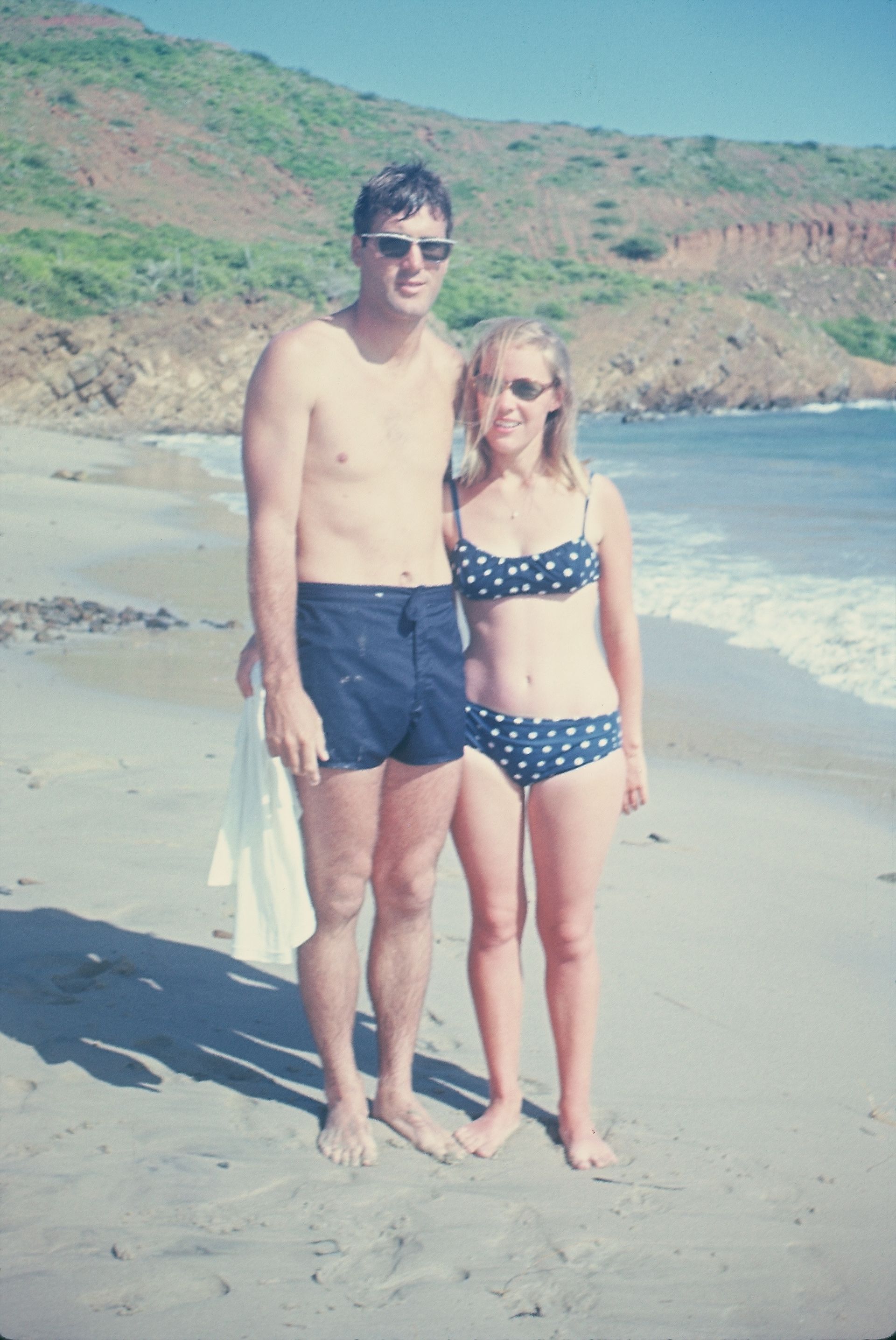 A man and a woman are posing for a picture on the beach
