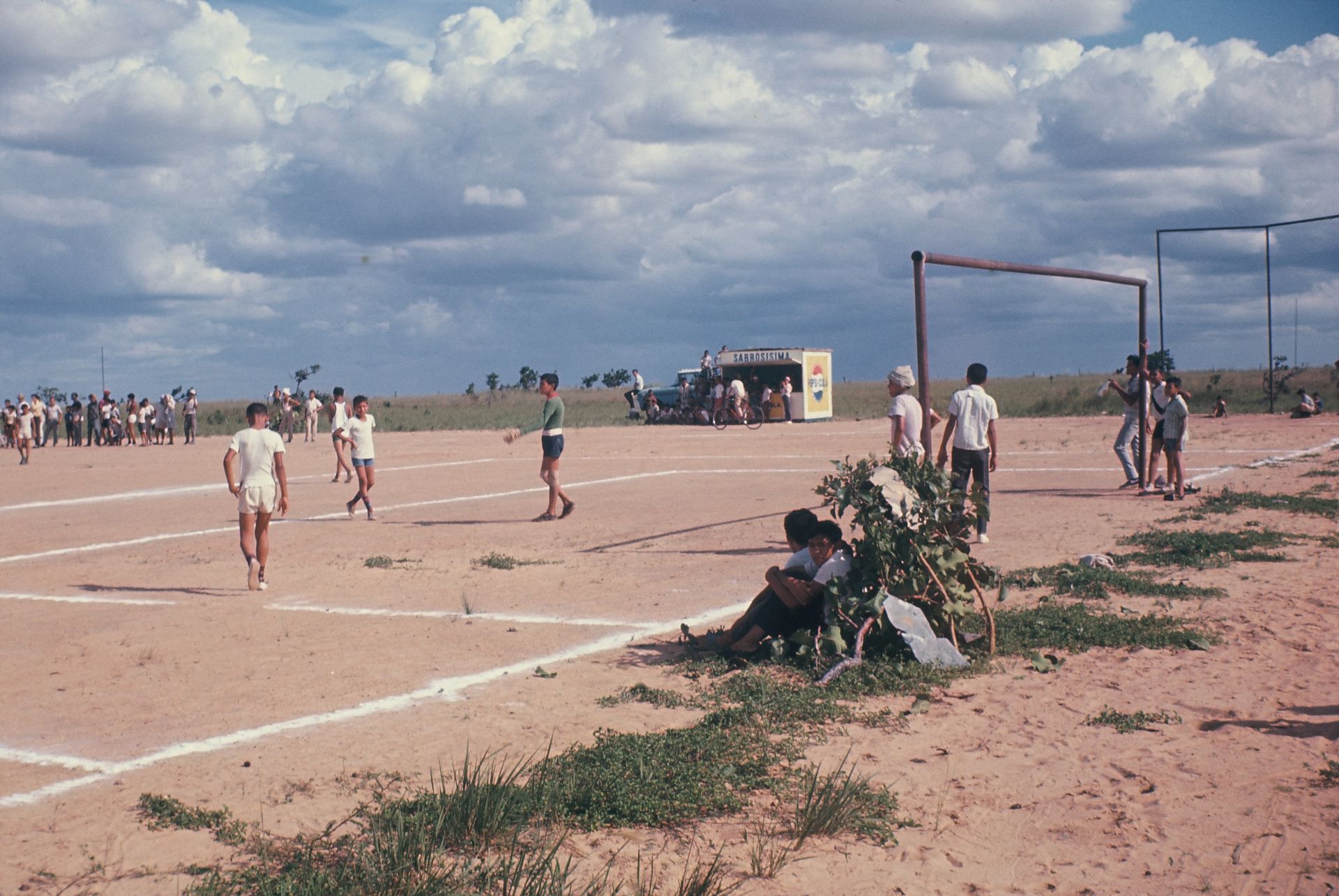 A group of people are playing soccer on a dirt field