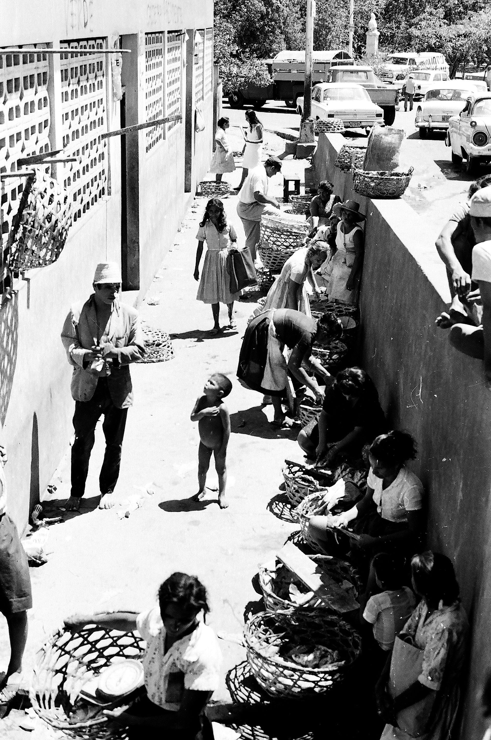 A black and white photo of a group of people on a sidewalk