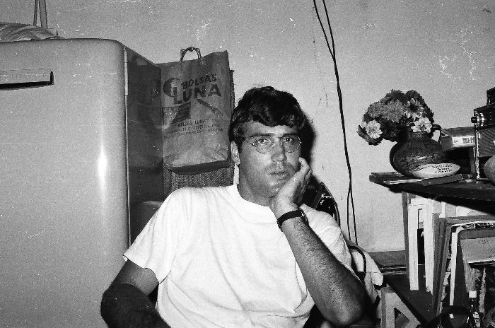 A black and white photo of a man sitting in front of a refrigerator