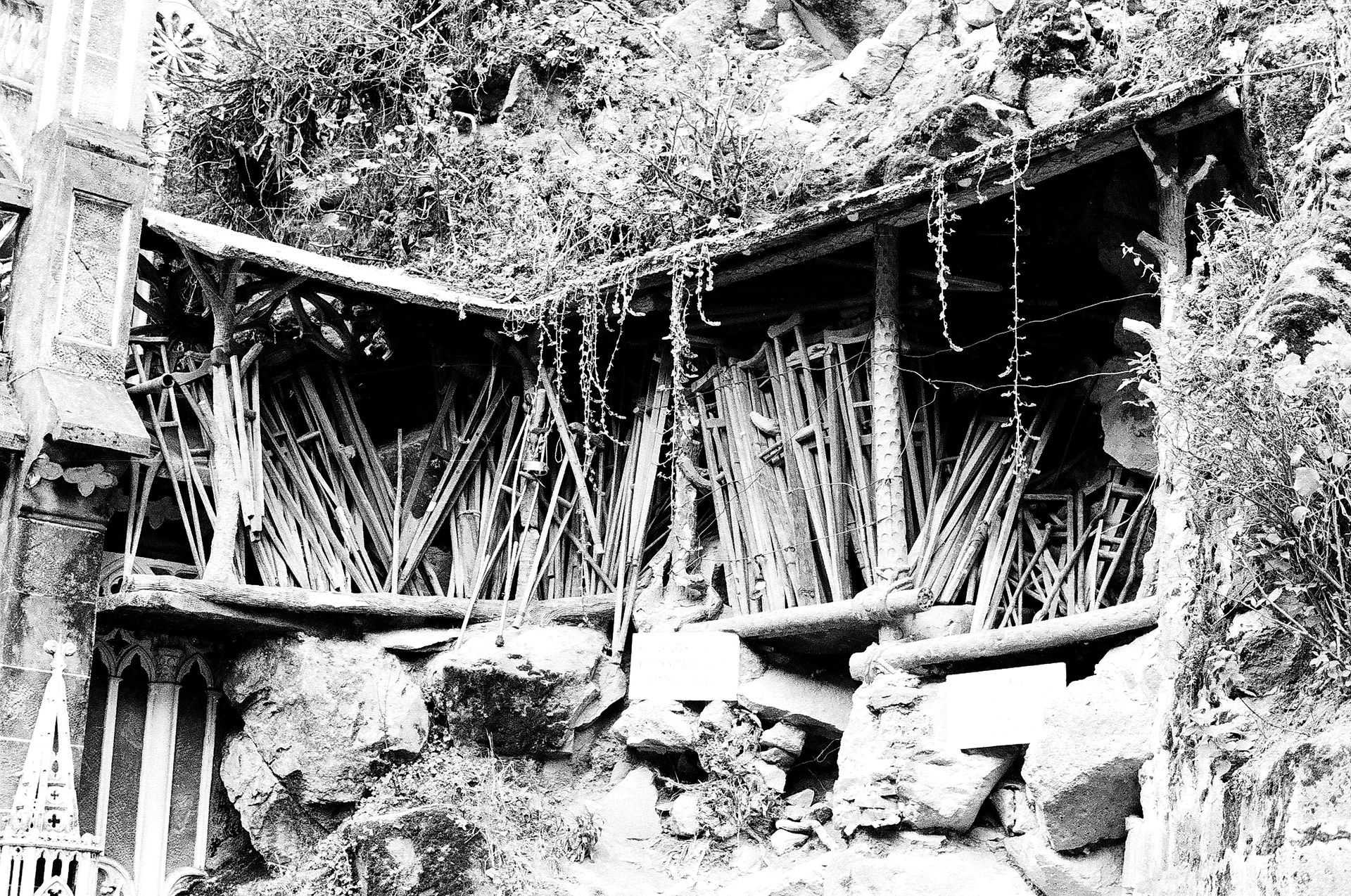 A black and white photo of a wooden structure in the woods.
