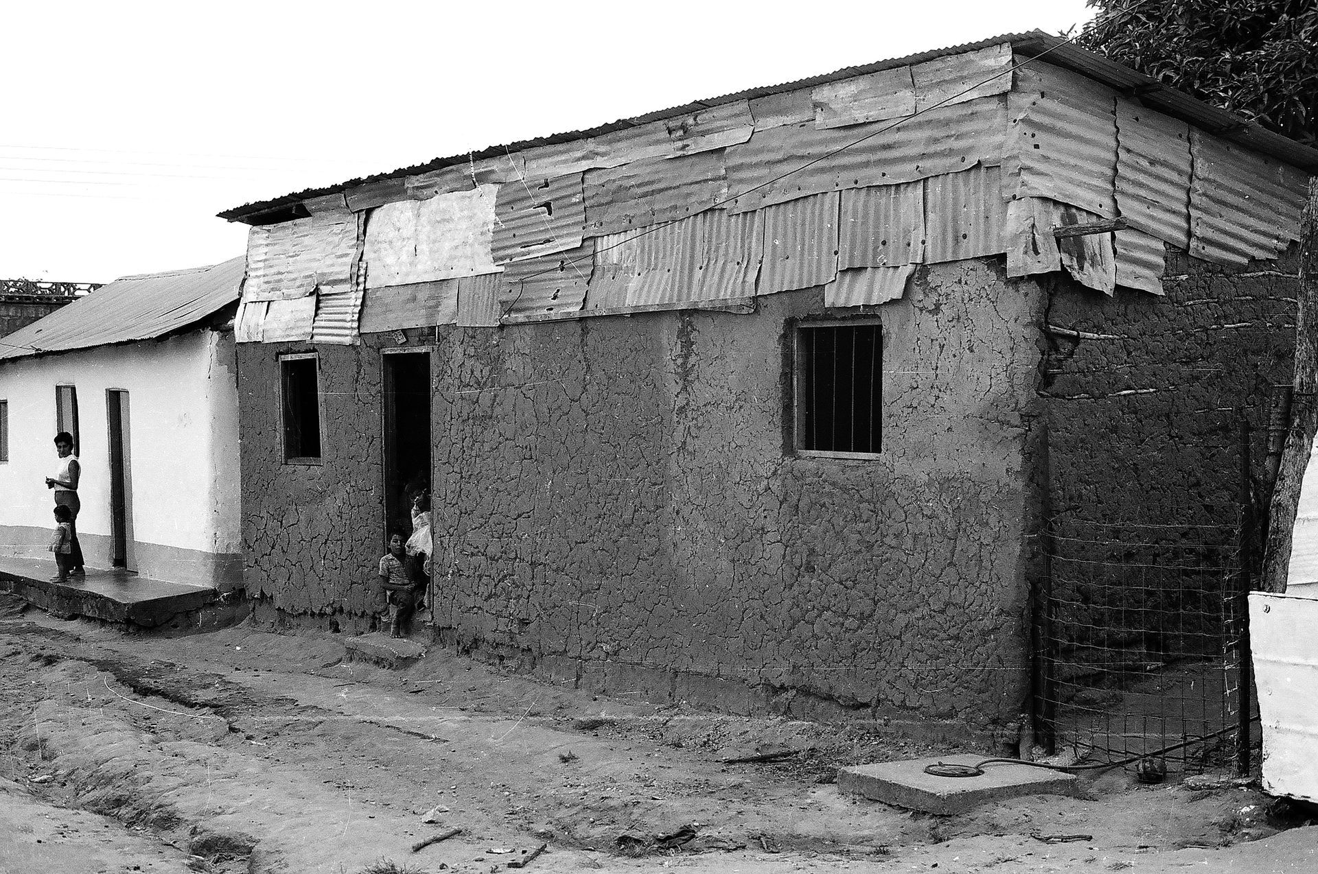 A black and white photo of a brick building with a wooden roof.
