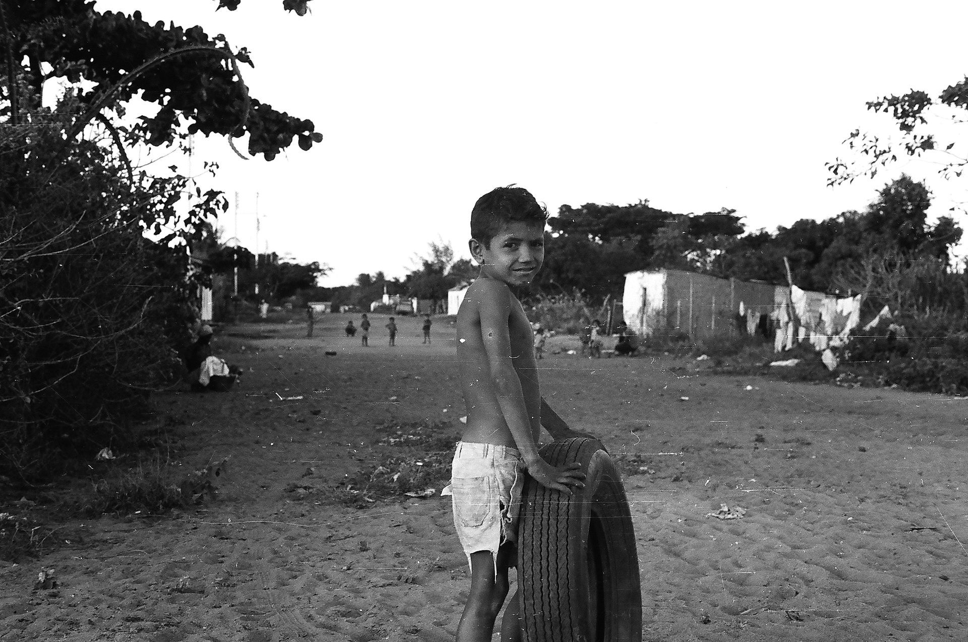 A black and white photo of a young boy holding a tire