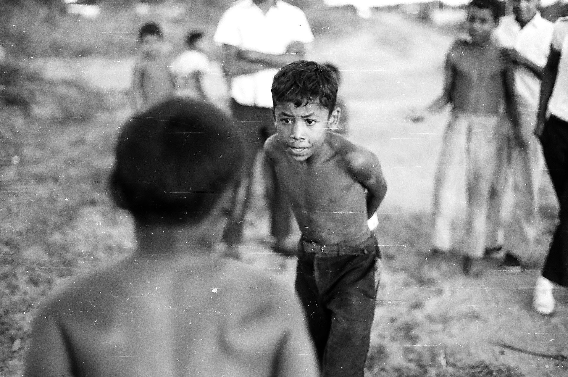 A black and white photo of a group of children playing in the dirt.