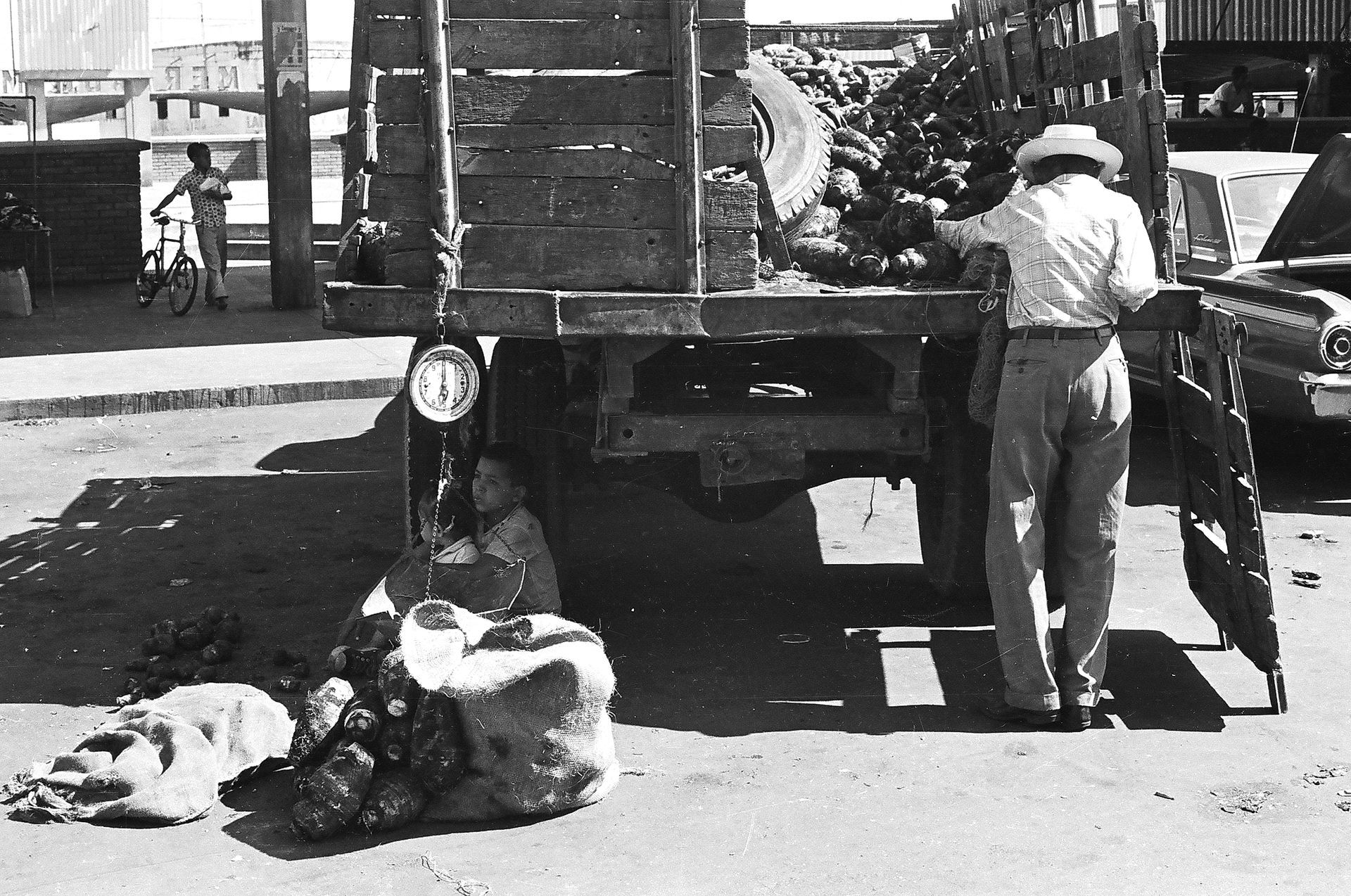 A black and white photo of a man loading garbage into a truck