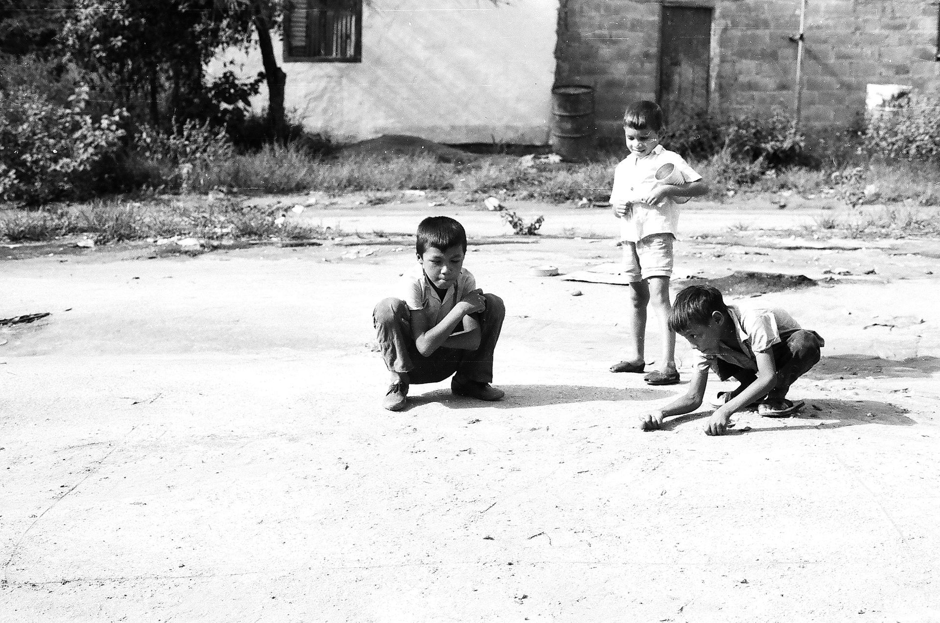 A black and white photo of three children playing on the ground