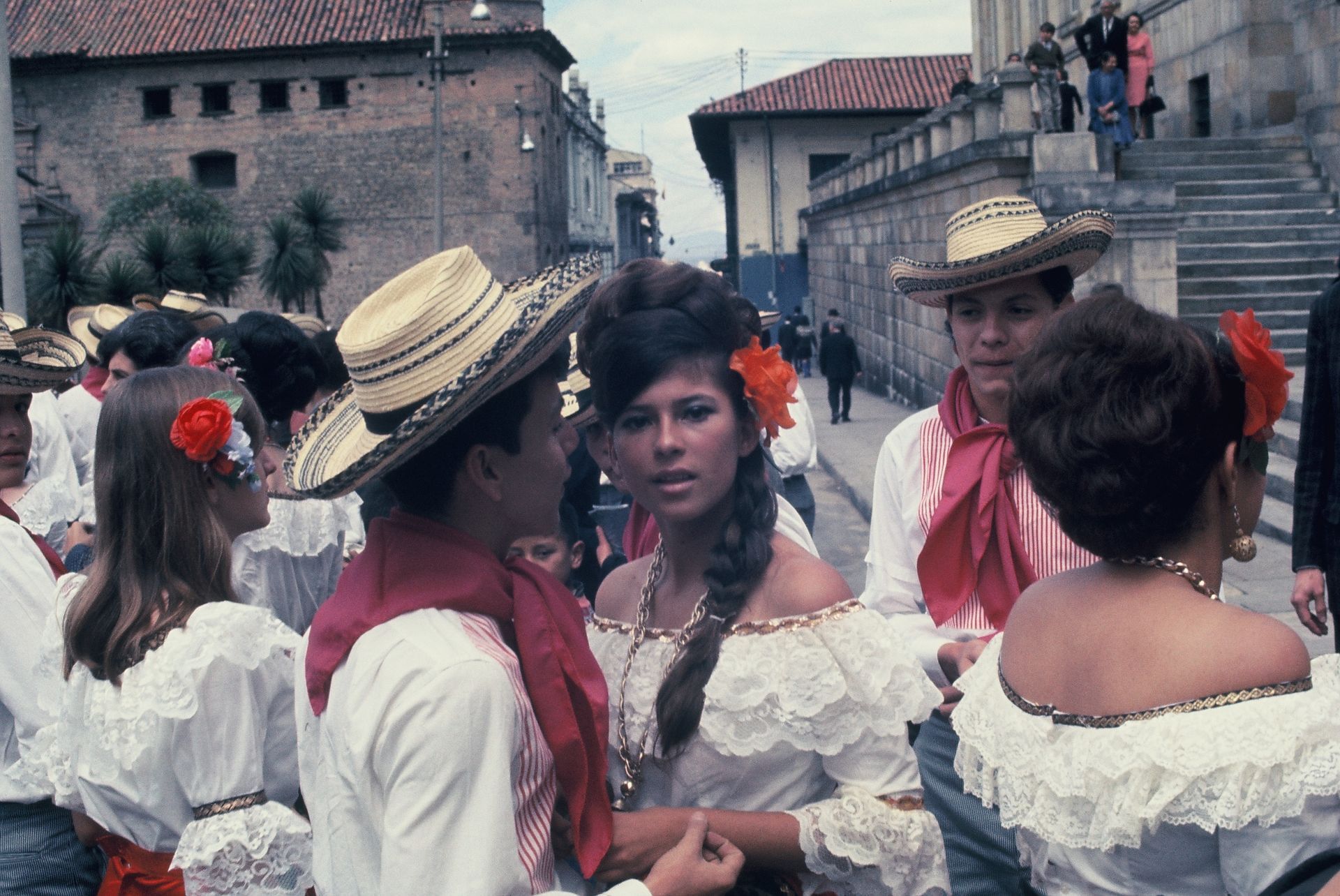 A group of people are standing on a street talking to each other