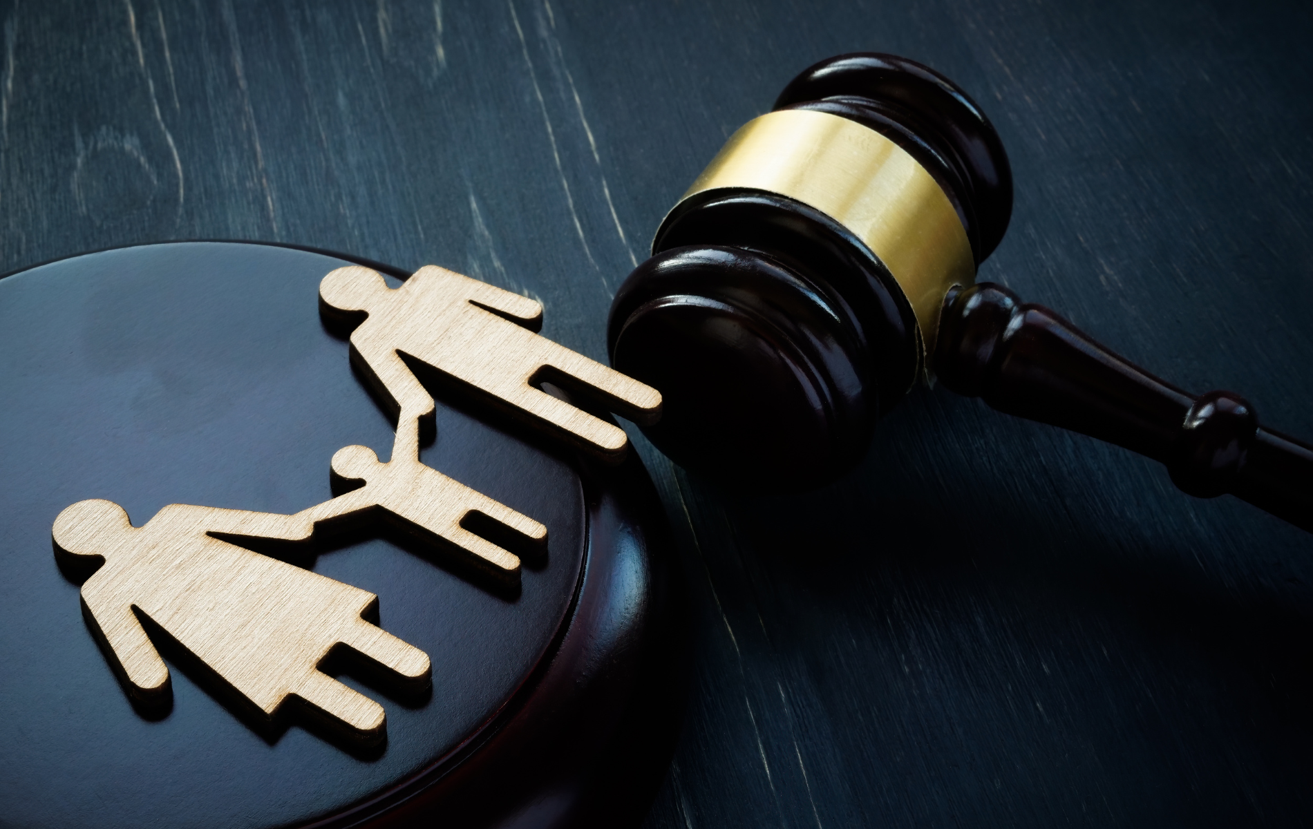 Wooden family figures with a gavel on a dark surface, symbolizing family law.